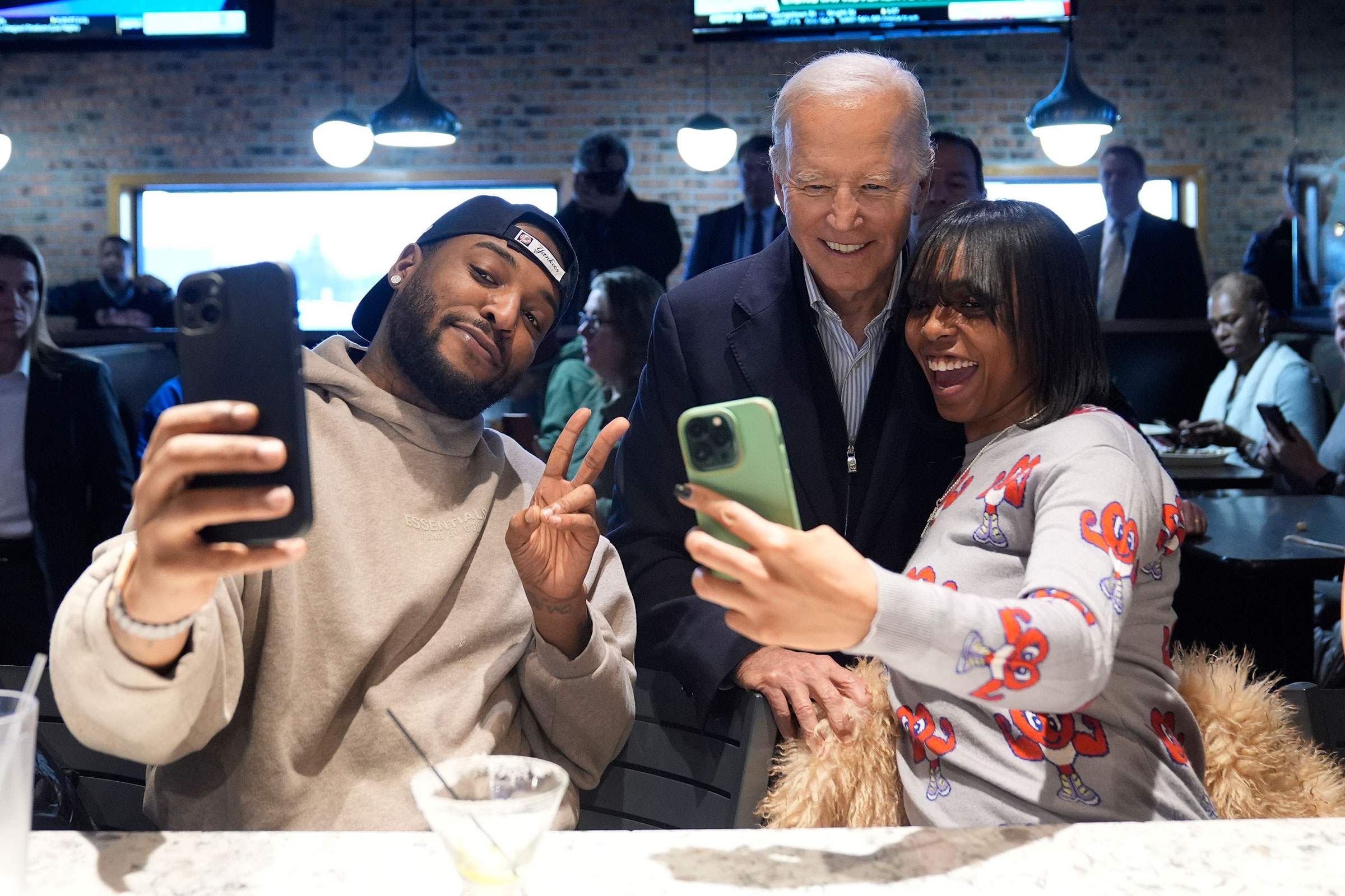 President Joe Biden, center, takes photos with patrons at They Say restaurant during a campaign stop Feb. 1, 2024, in Harper Woods, Michigan. Evan Vucci/AP
