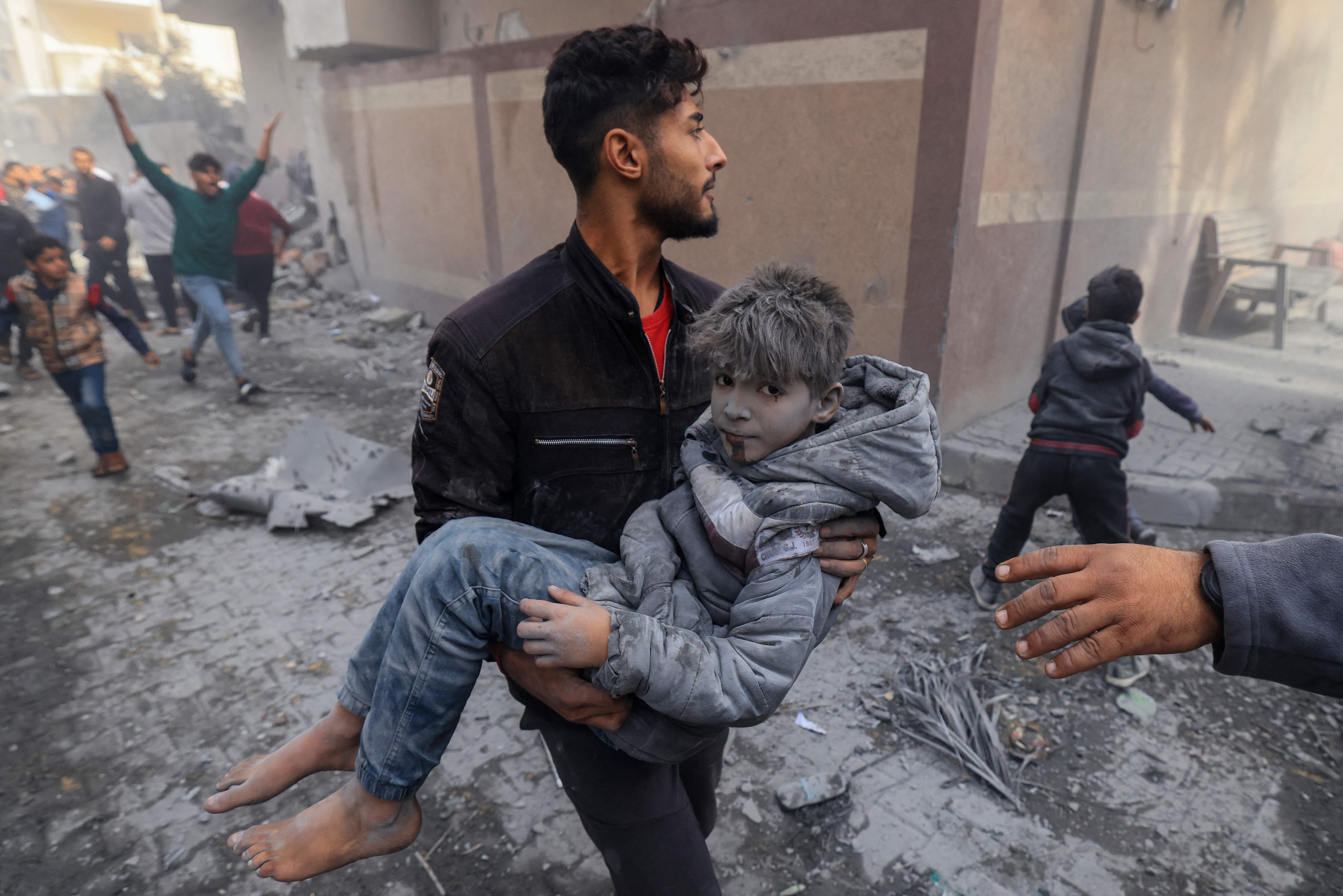 A man carries a child injured in an Israeli strike on Rafah, in southern Gaza, on November 20, 2023.