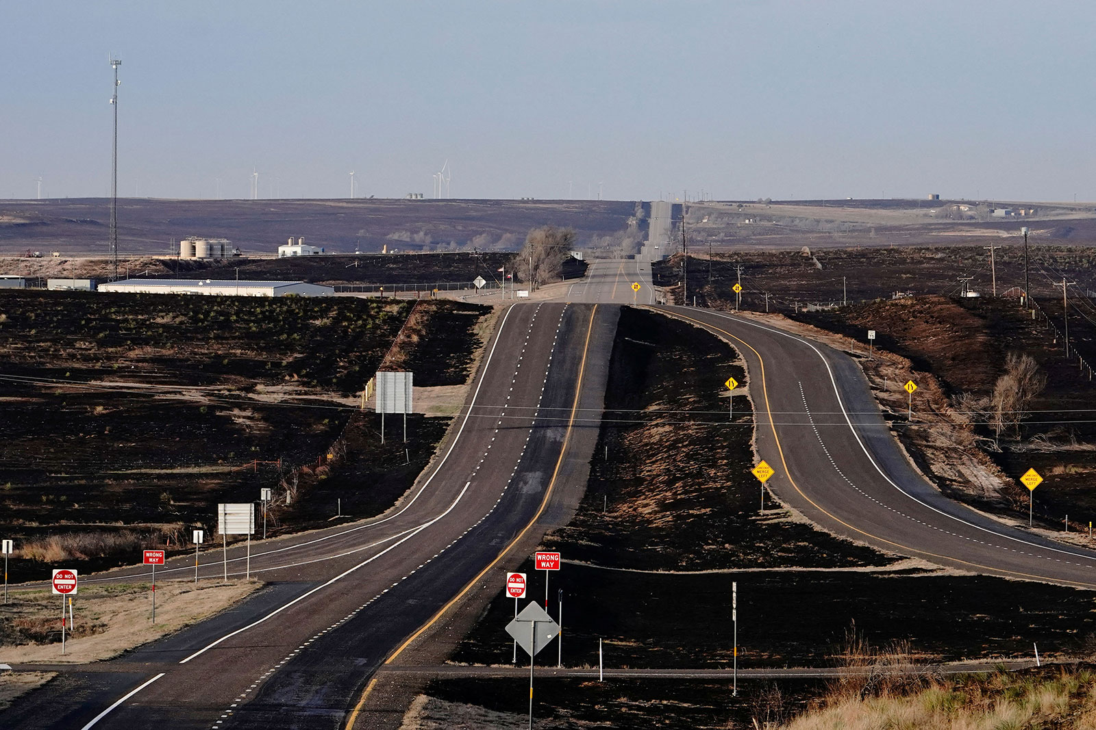 Burned grassland is seen next to a highway.