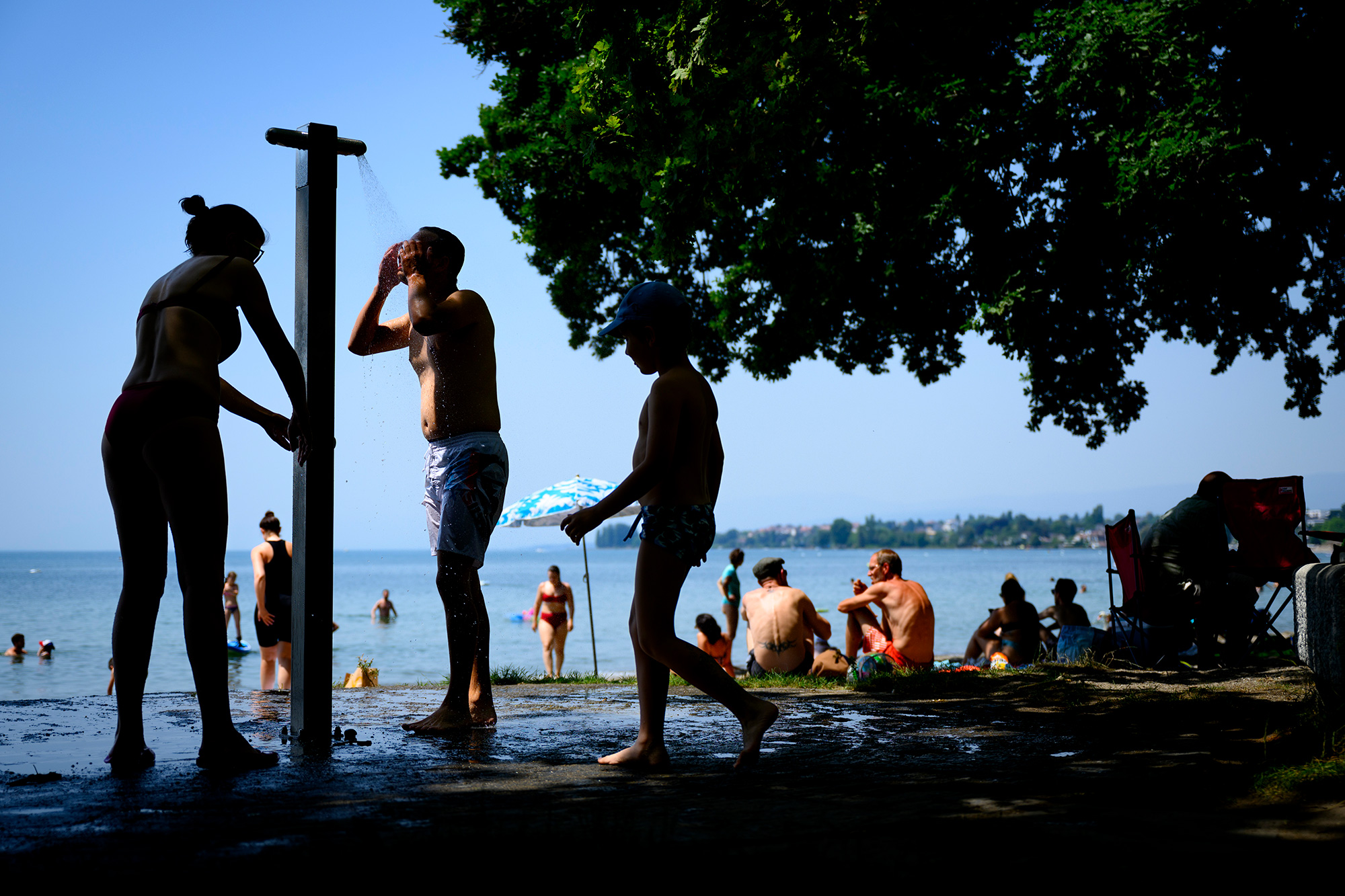 People cool off with a shower during warm weather at Vidy beach on Lake Geneva in Lausanne, Switerland, on Tuesday, June 19.