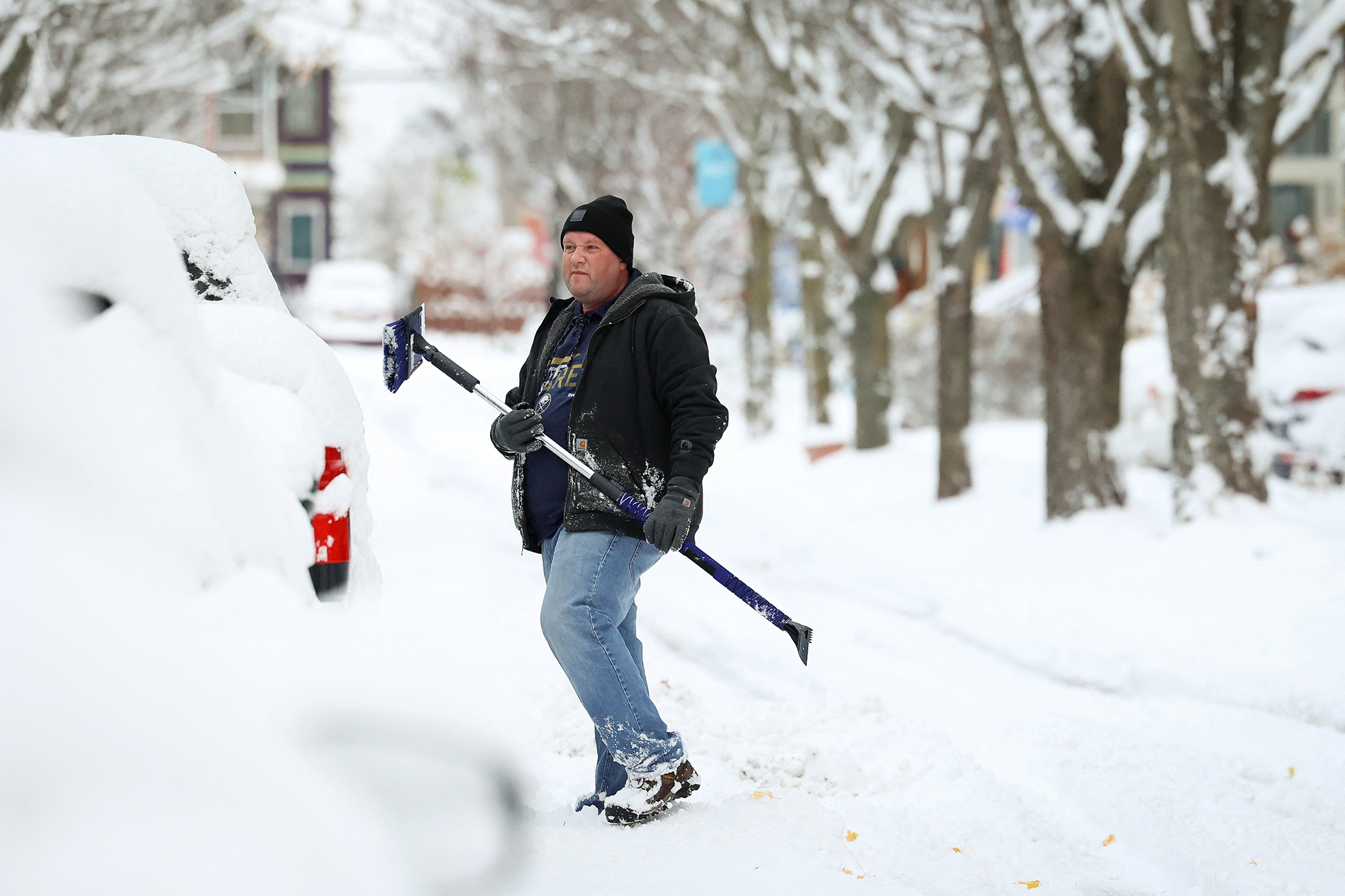 A resident cleans a vehicle on the street during a snowstorm as extreme winter weather hits Buffalo, New York, Friday.