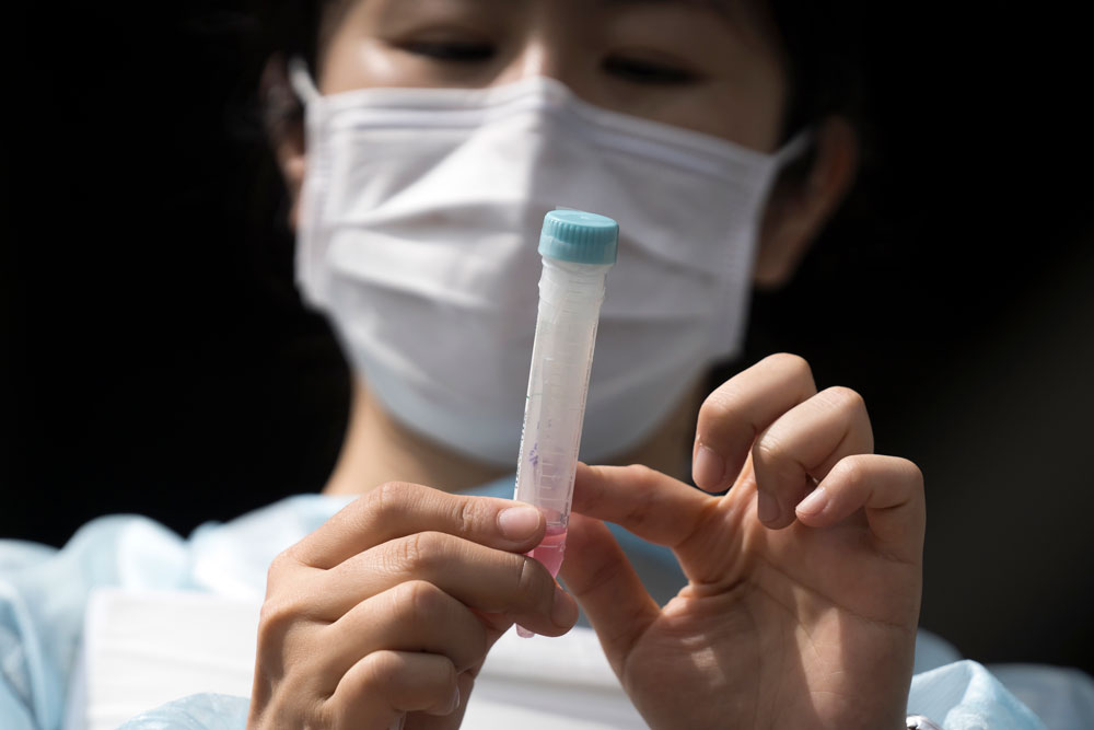 A medical staff member holds a container of a swab sample for a Covid-19 polymerase chain reaction (PCR) test during a rehearsal at a testing site outside Kashima Soccer Stadium on May 10, in Kashima, Japan. 