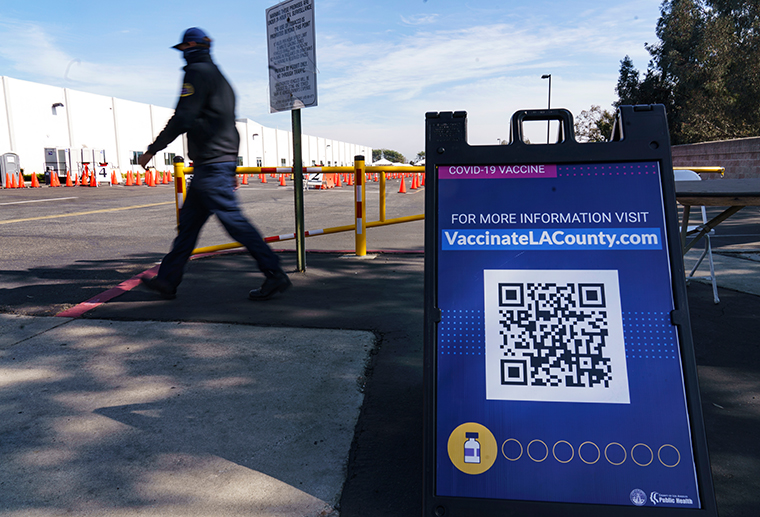 A COVID-19 vaccine poster directs motorists to the website: "VaccinateLACounty.com" outside the mass vaccination site at the parking lot of L.A. County Office of Education headquarters in Downey, Calif., Wednesday, Feb. 3, 2021. 