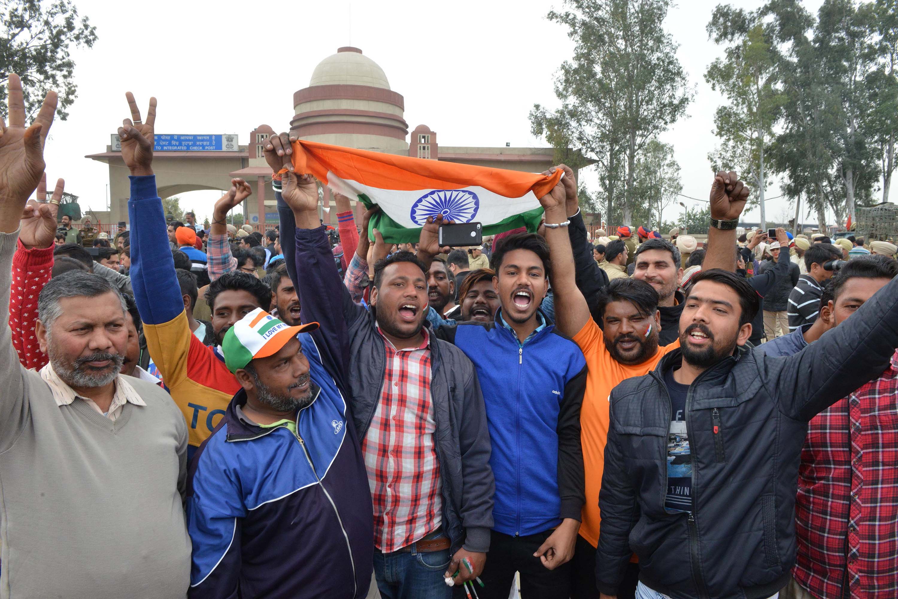 Indian men shout slogans and wave the national flag near the India-Pakistan border in Wagah on March 1, 2019, as they wait for Pakistan to return an Indian Air Force pilot.