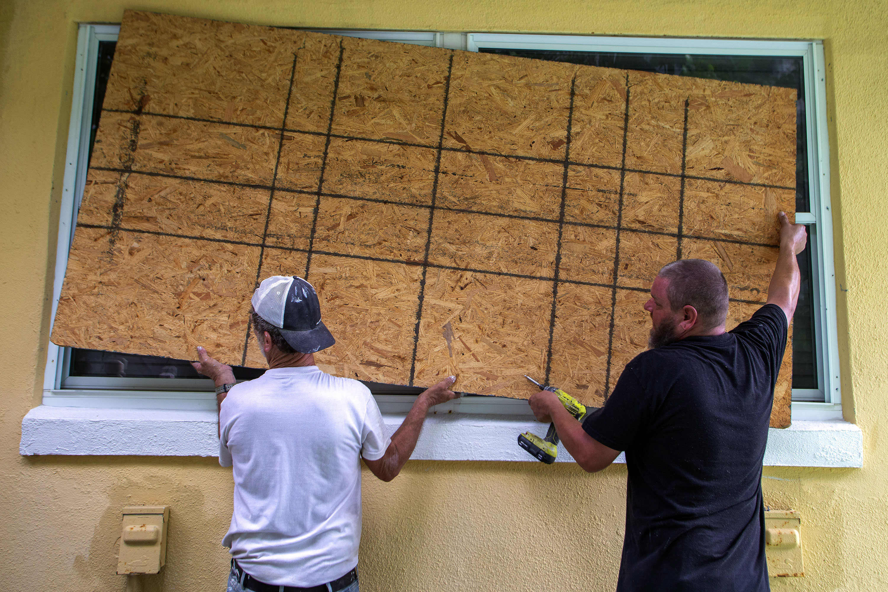 Residents place a wooden board to protect a house in St. Petersburg, Florida, on Monday.