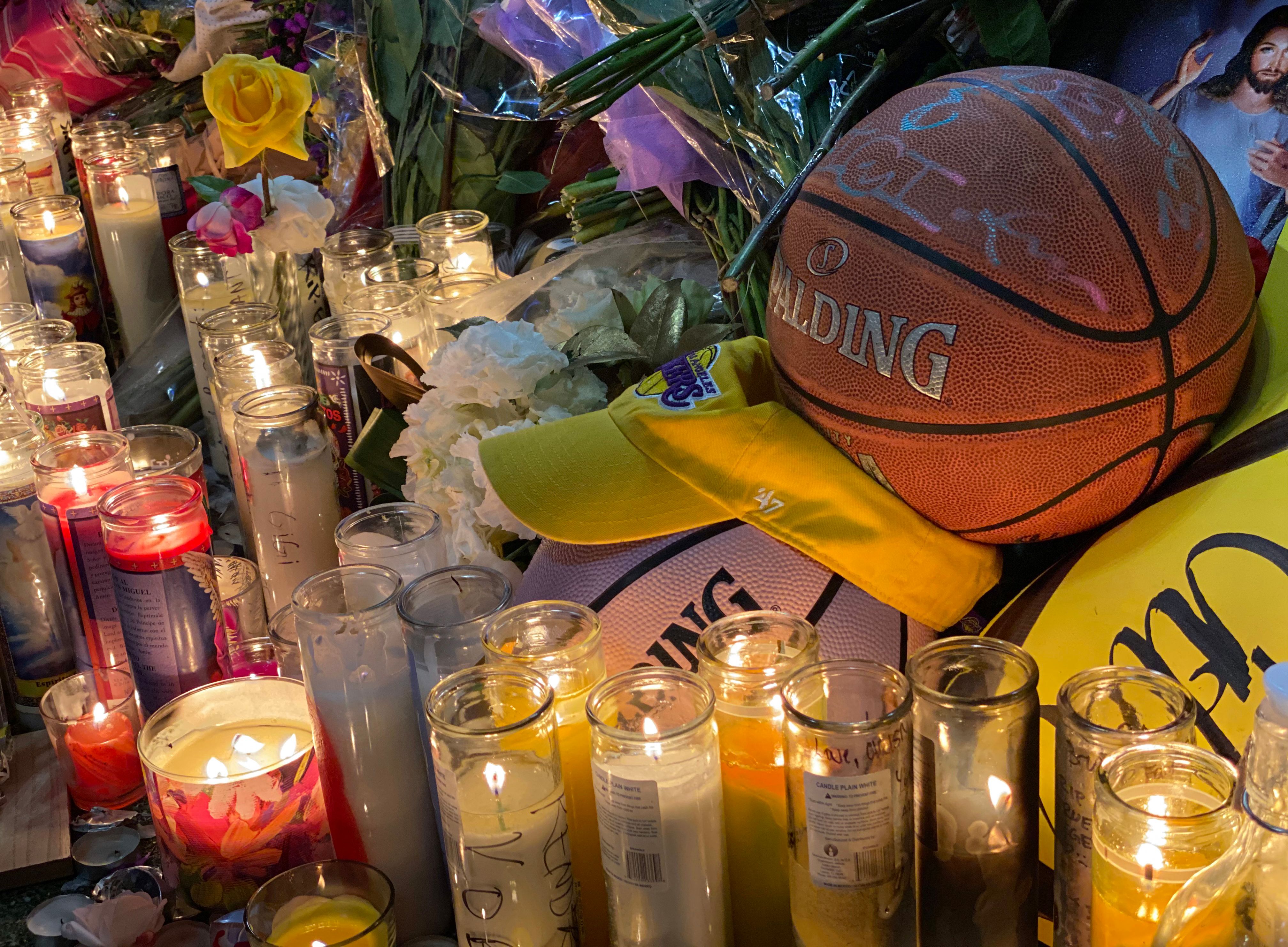 Candles are displayed at a makeshift memorial in front of a mural in downtown Los Angeles.