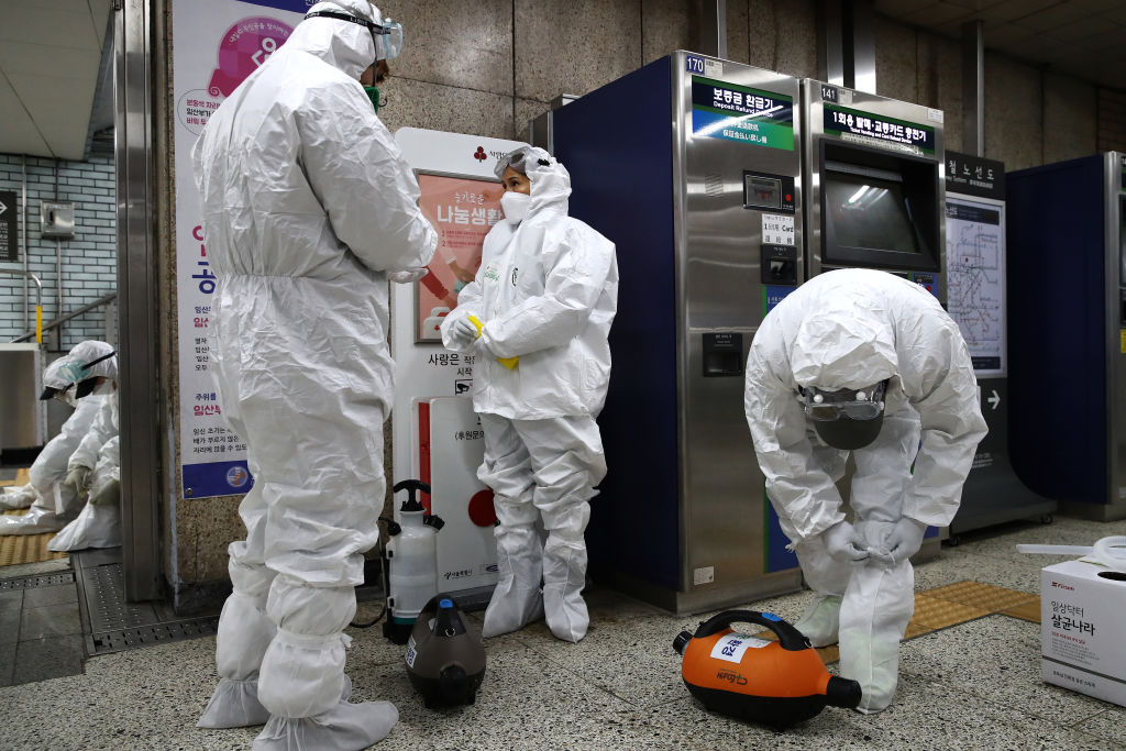 Workers wearing protective gear prepare to disinfect against the coronavirus at a subway station in Seoul, on February 21, 2020.