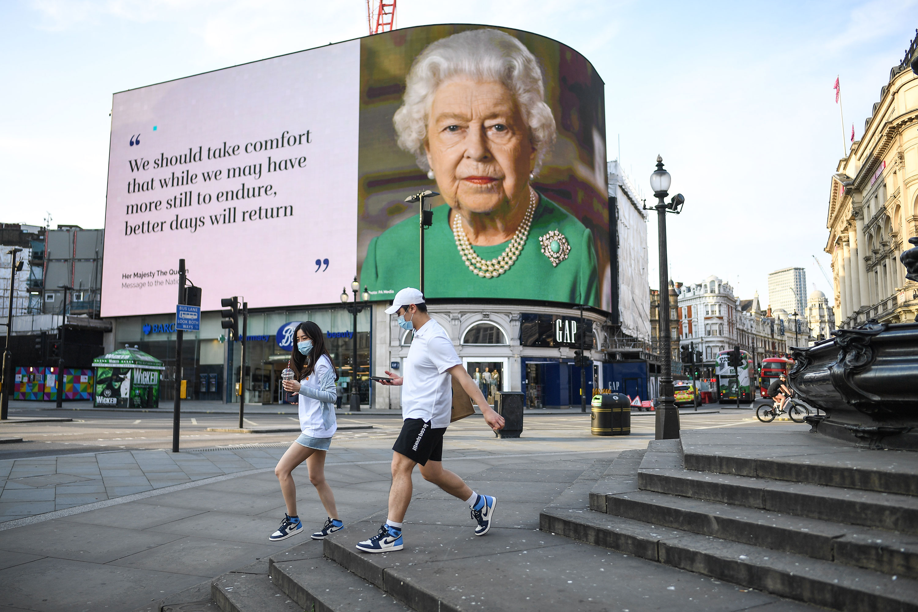 People walk past an image of Queen Elizabeth in Piccadilly Circus in London on April 9.
