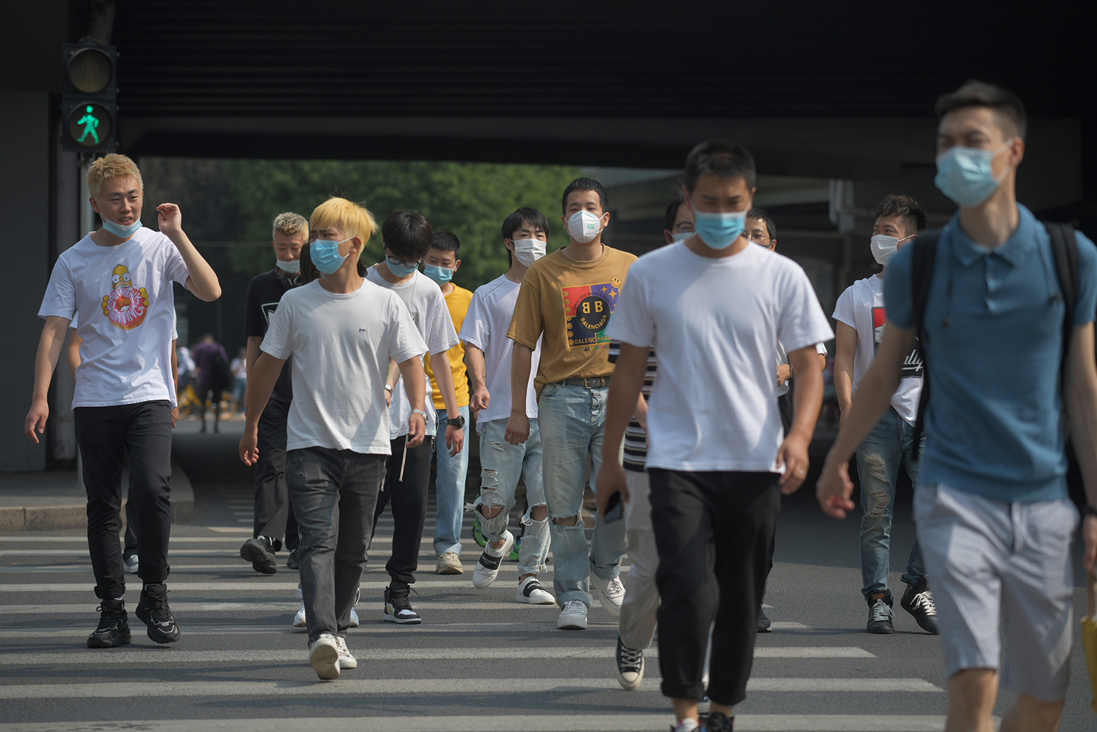 People wear masks as they cross a road in Beijing on June 28.