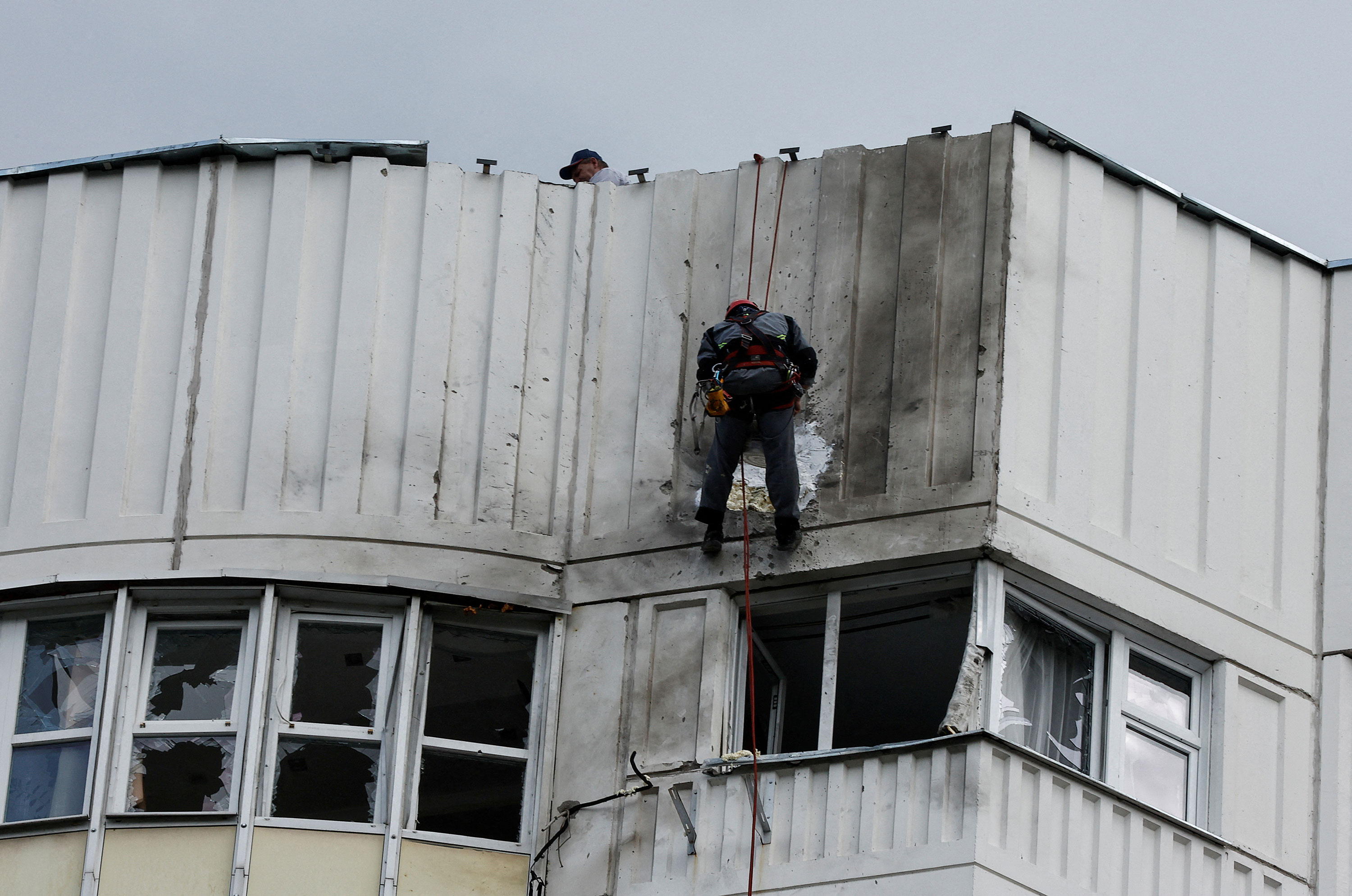Workers repair damage on the roof of an apartment building after a drone attack in Moscow on Tuesday.