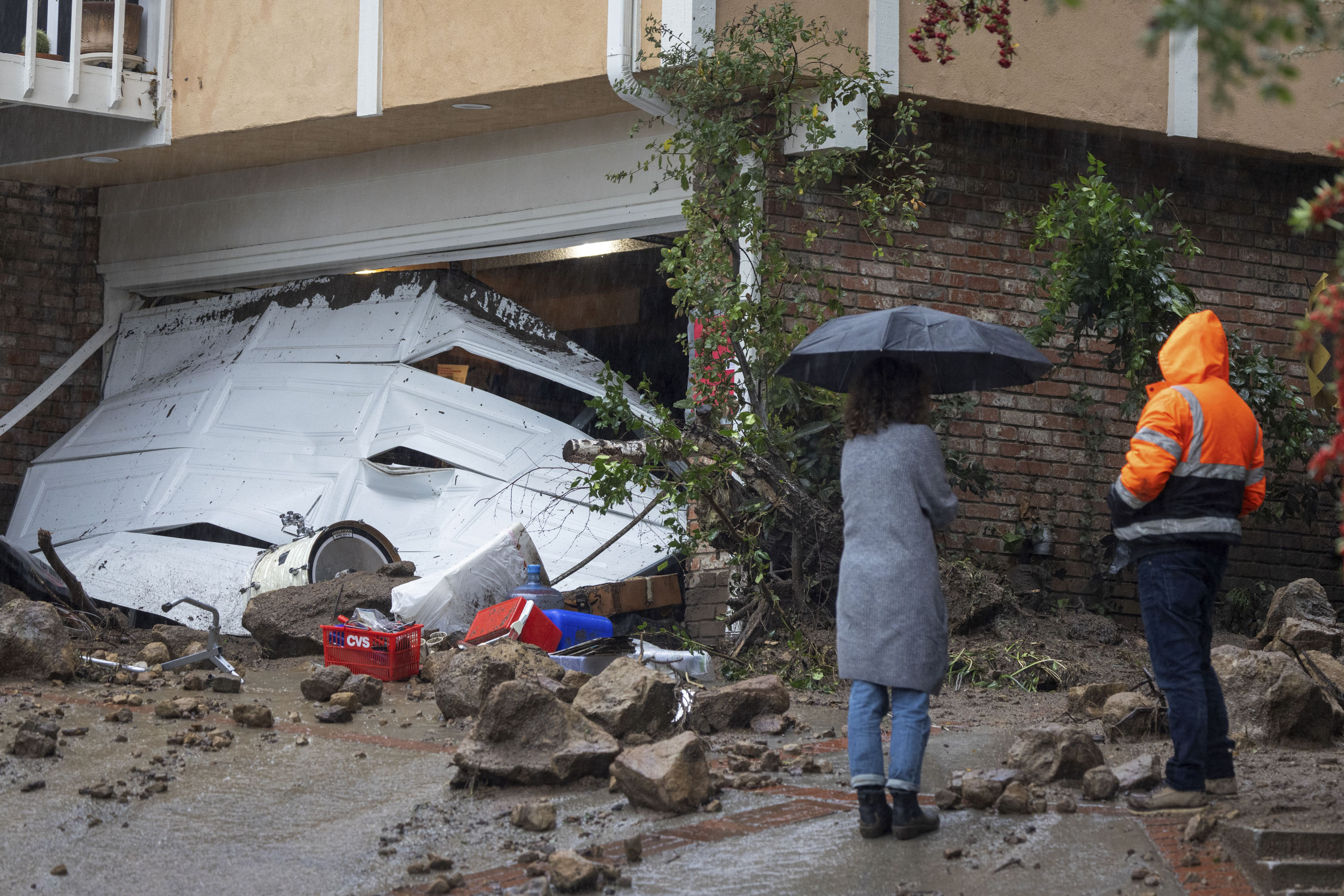 People stand near a garage damaged during a landslide and flash floods, in the Studio City area of Los Angeles, on February 5.
