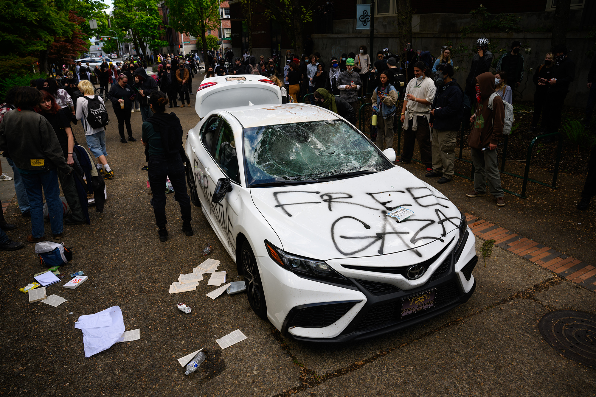 Protesters stand around a defaced car, after a man drove it toward a crowd at Portland State University on May 2. 