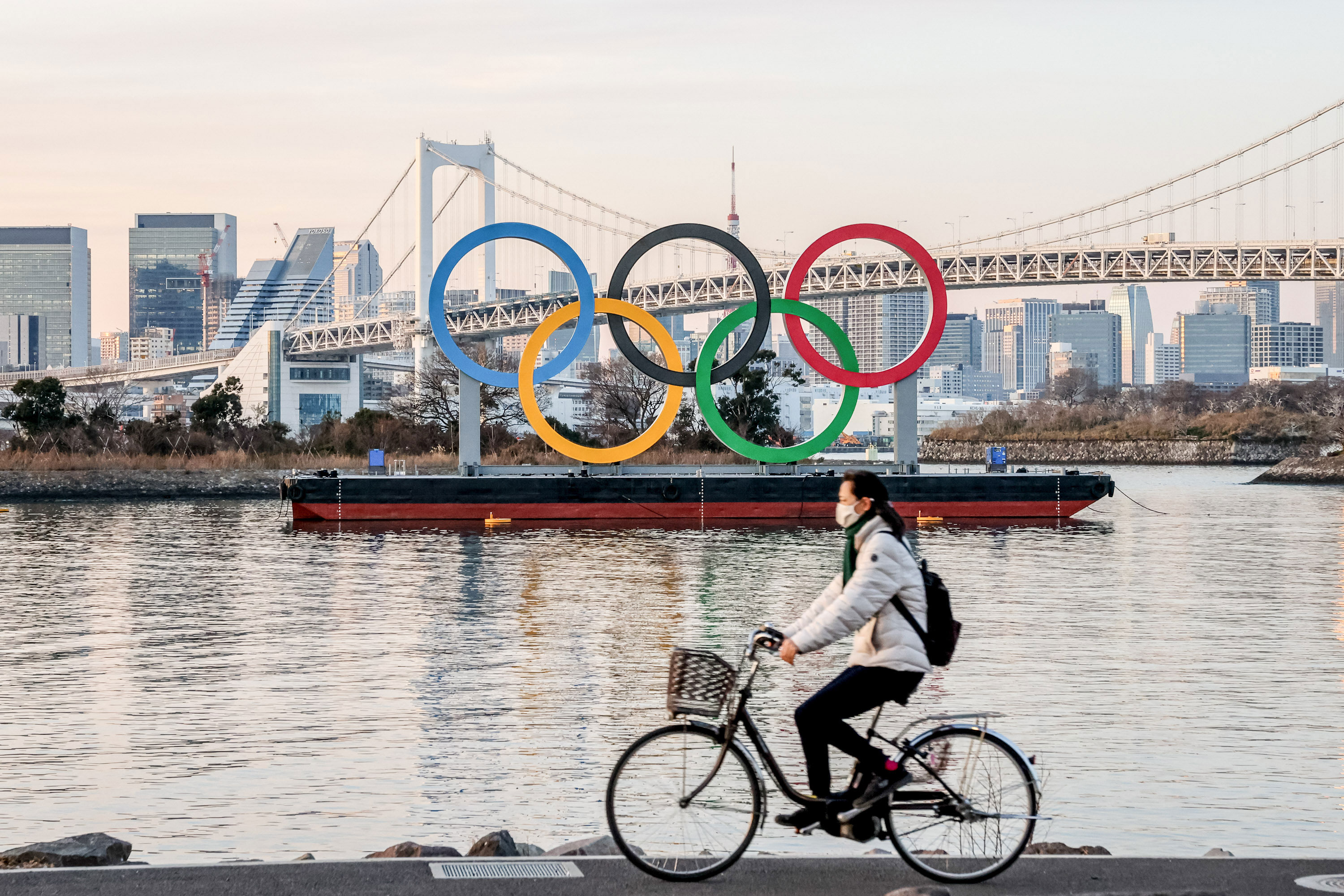 A person rides by the Olympic symbol in Tokyo on January 25.