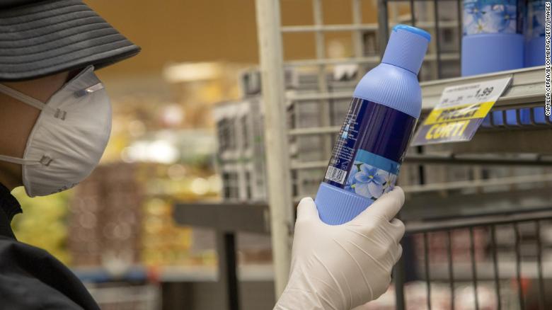 A customer wearing a protective face mask and gloves reads a cleaning product label in a grocery store in Milan, Italy, on Tuesday, February 25. 