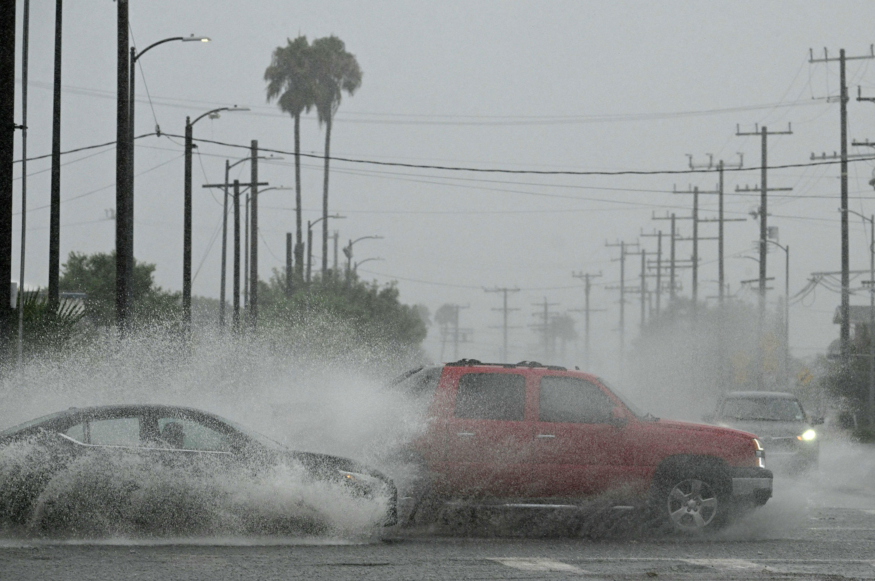 Vehicles splash up water during heavy rains from Tropical Storm Hilary in Los Angeles on Sunday, August 20. 