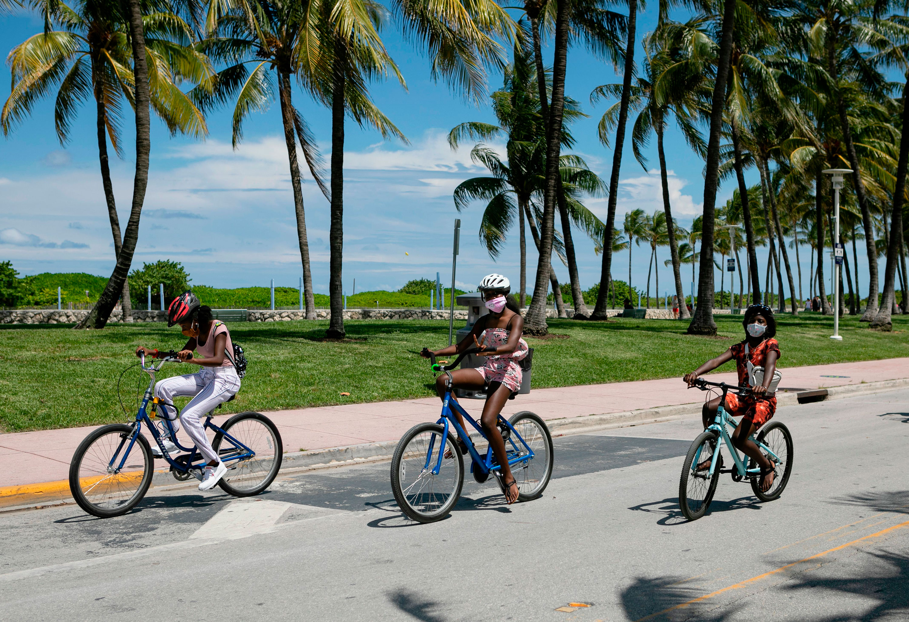 People wear face masks while riding bicycles on Ocean Drive in Miami Beach, Florida, on June 16.