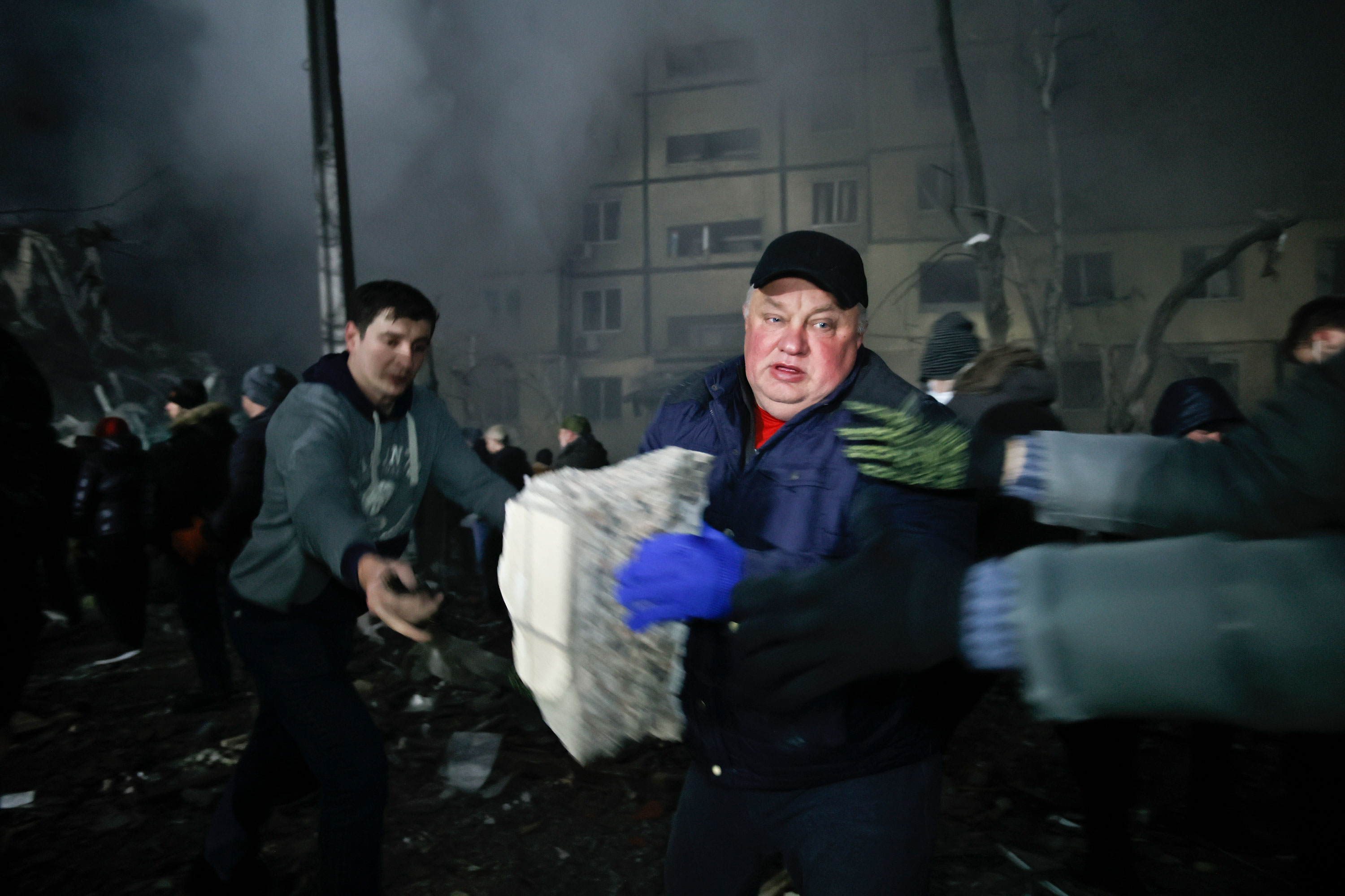 Local residents clear the rubble after a Russian rocket hit a multistory building in Dnipro on Saturday.