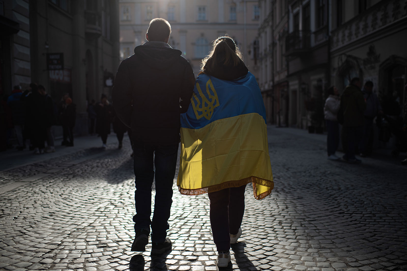 A man and a woman wrapped in the Ukrainian national flag walk the street on March 20 in Lviv.