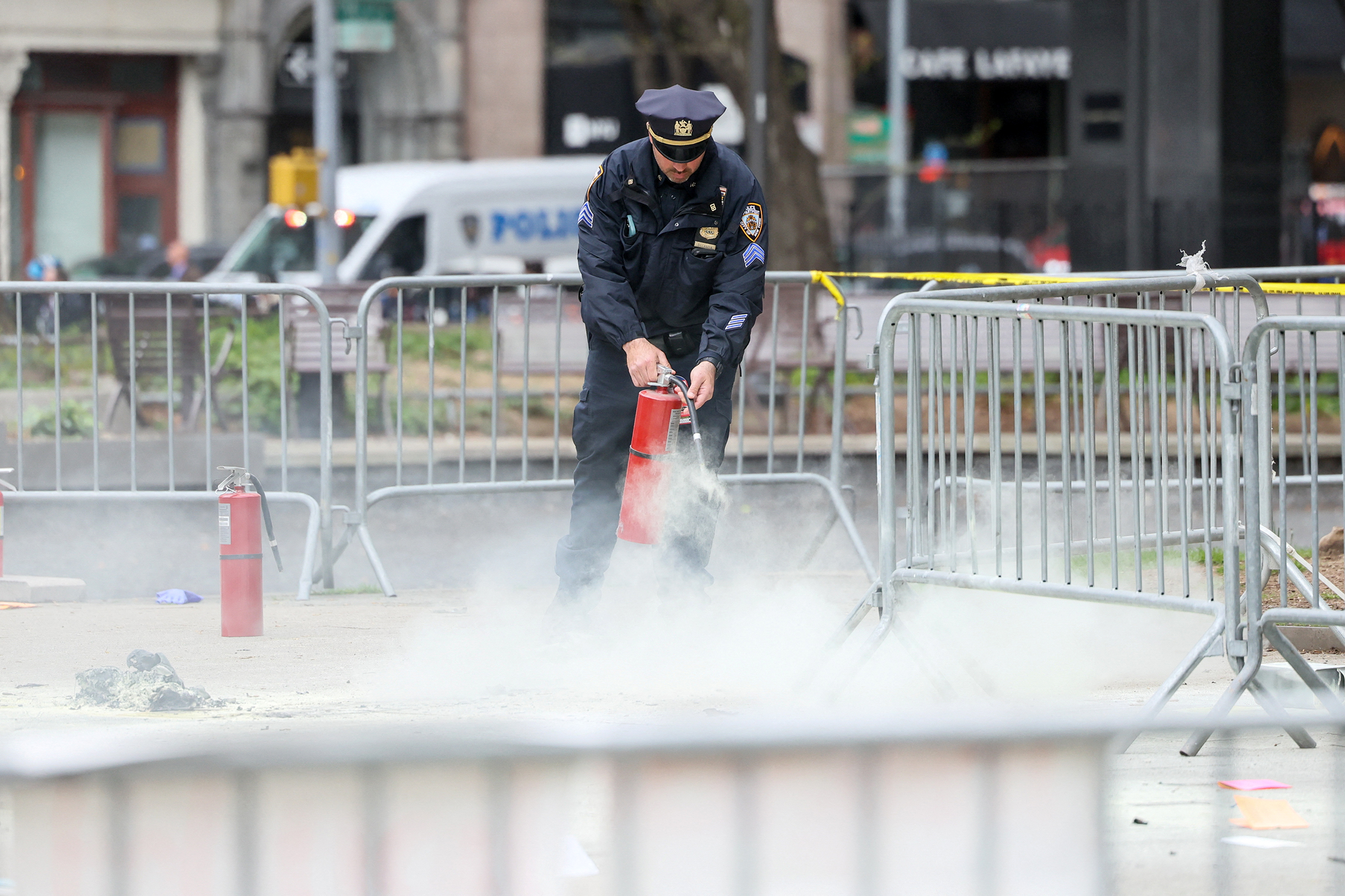 A police officer uses a fire extinguisher as emergency personnel respond to a report of a person covered in flames outside the courthouse where former President Donald Trump's criminal hush money trial is underway in New York on Friday.