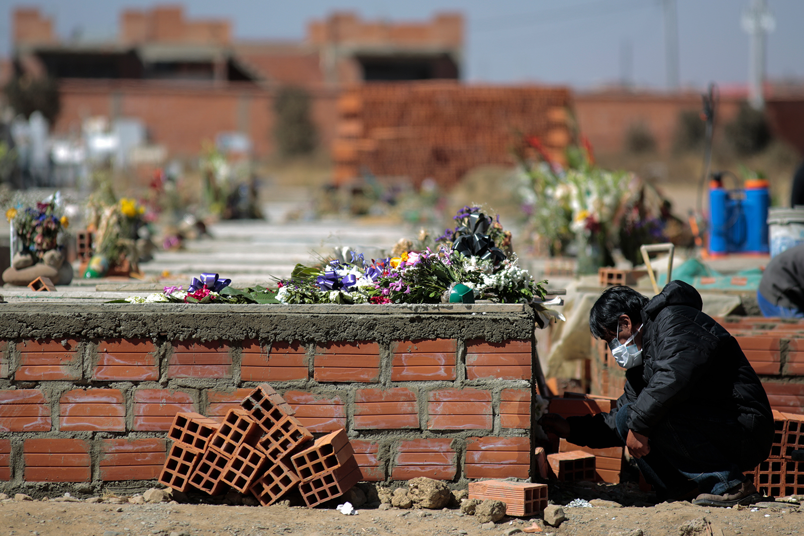 A mourner writes the name of the deceased on the fresh cement at Mercedario Cemetery in El Alto, Bolivia, on July 29.