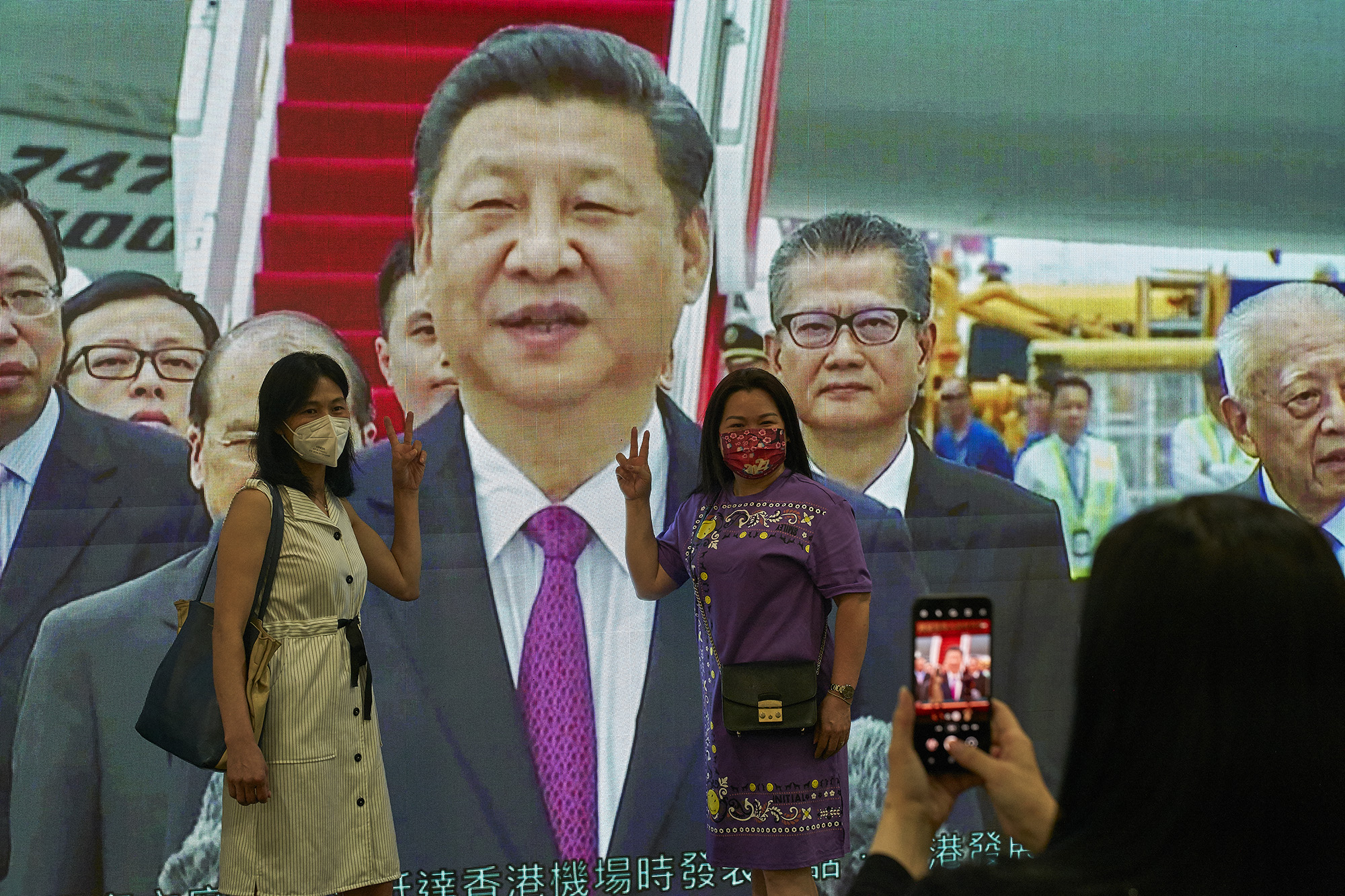 Two women take a photo in front of a poster of the Chinese leader Xi Jinping at an exhibition hall in Hong Kong on June 28.