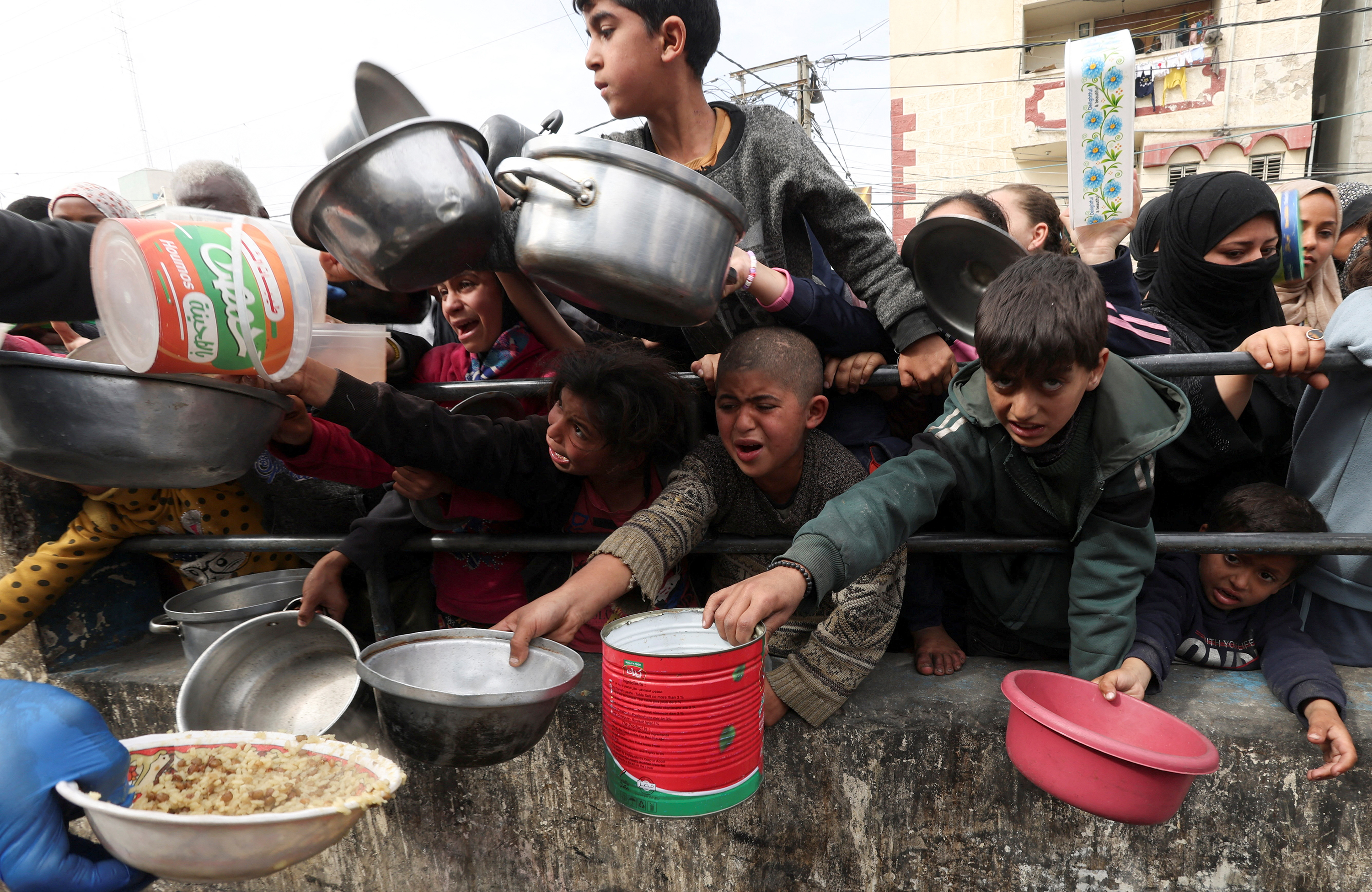 Children wait to receive food cooked by a charity kitchen in Rafah, Gaza, on February 13.