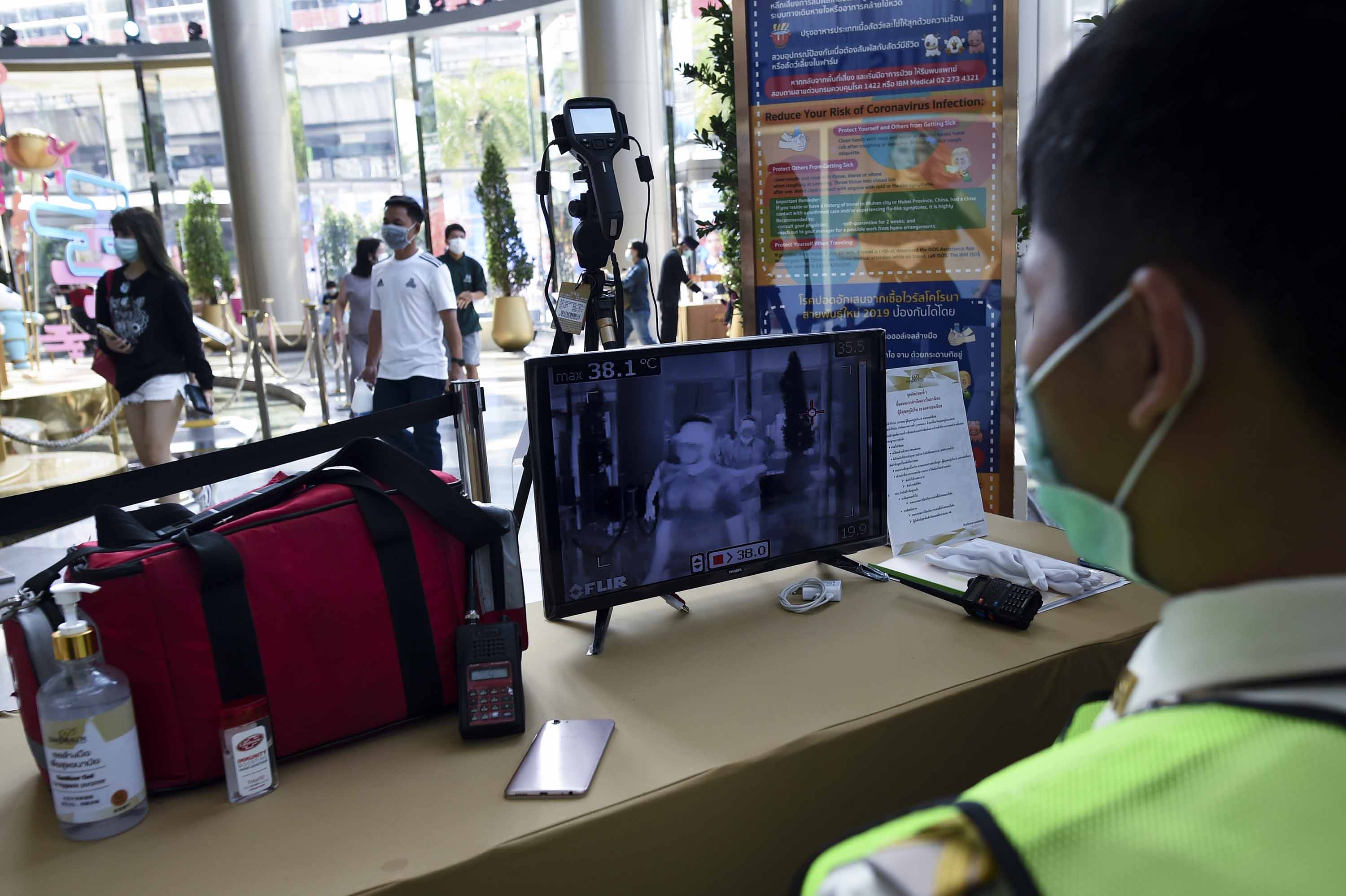 Security personnel use a thermal scanner to check people entering a department store in Bangkok, Thailand, on Friday.