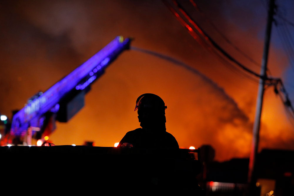 A police watch as firefighters work during demonstrations Thursday, May 28, in St. Paul, Minnesota.