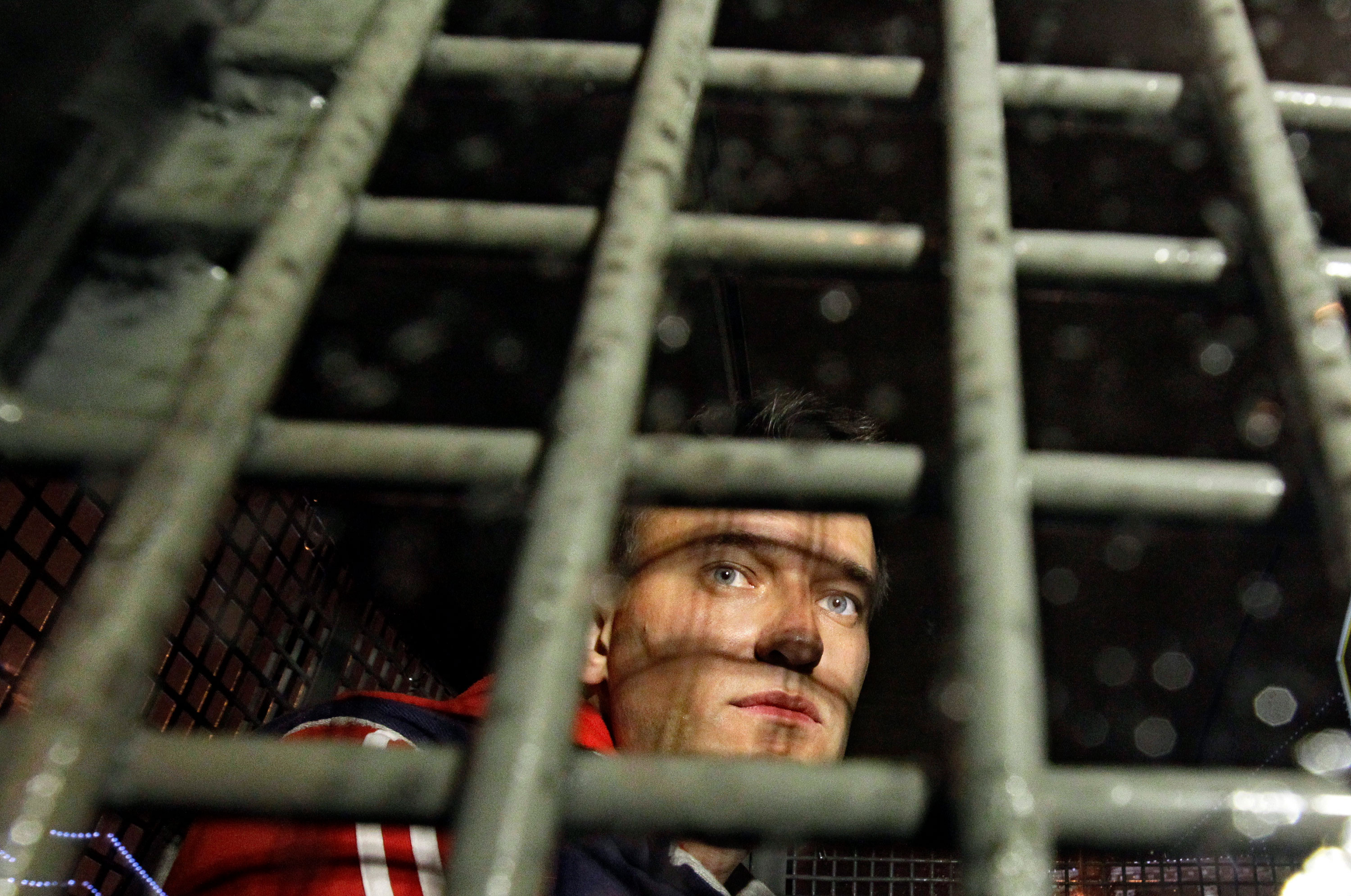 Alexey Navalny is seen behind the bars of a police van after he was detained during protests in Moscow in 2012.