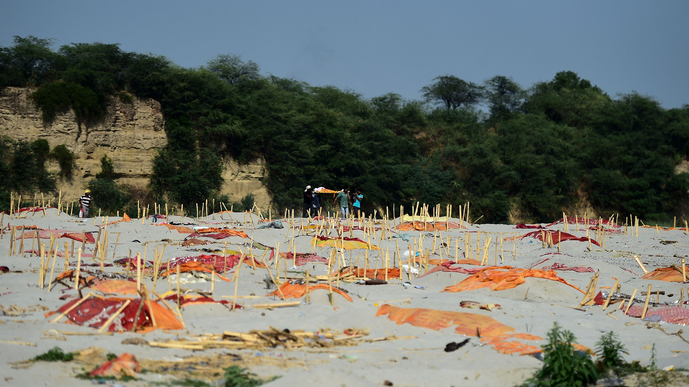 Relatives carry a body past shallow graves of suspected Covid-19 vicitims near a cremation ground on the banks of the Ganges River in Shringverpur village, India, on May 15. 