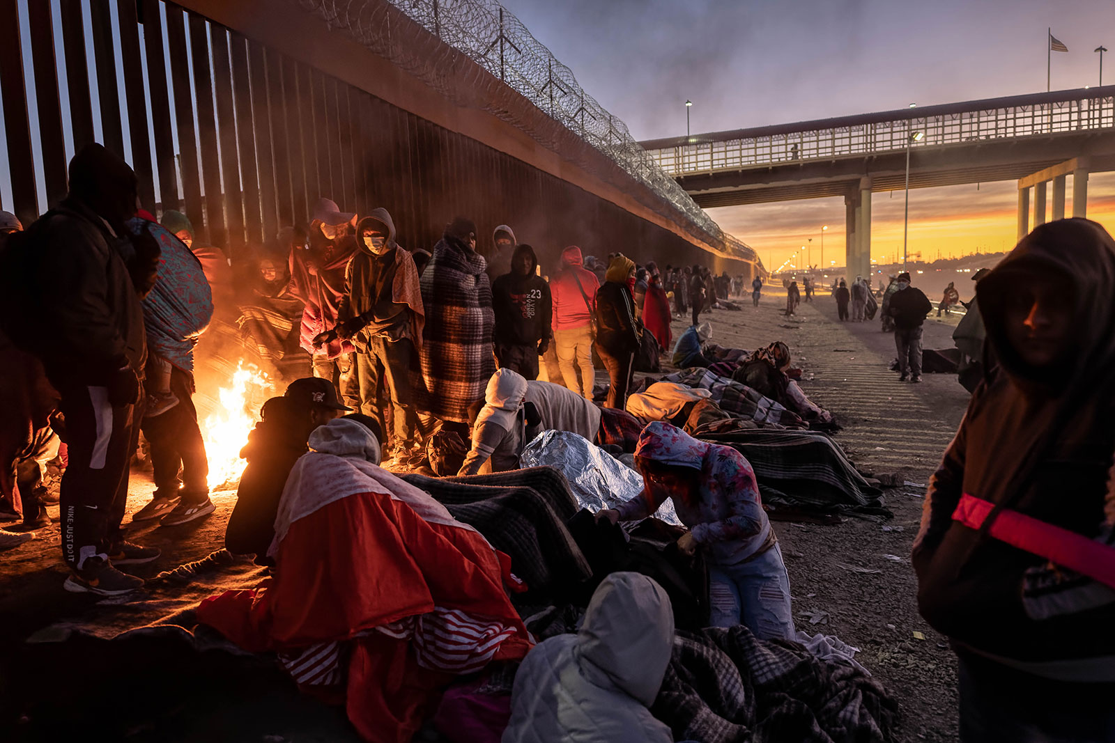 Migrants warm themselves by a fire next to the US-Mexico border fence on December 22 in El Paso, Texas.