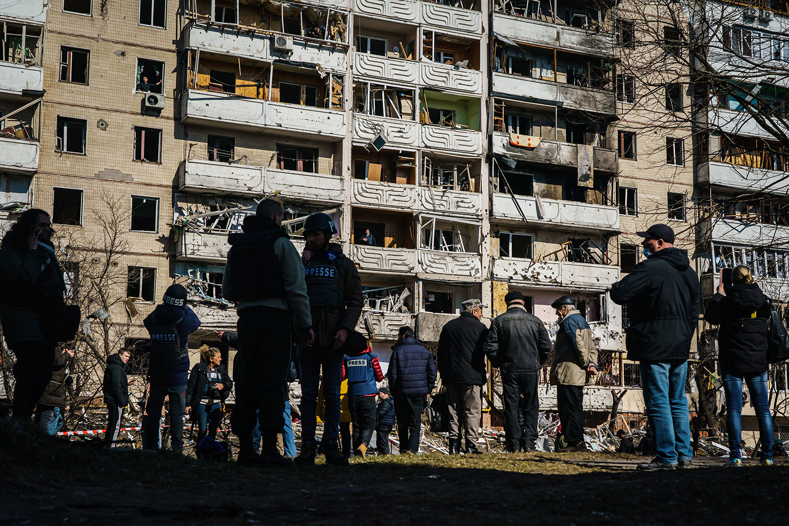 Reporters and local residents stand outside a damaged residential building in Kyiv on March 15.