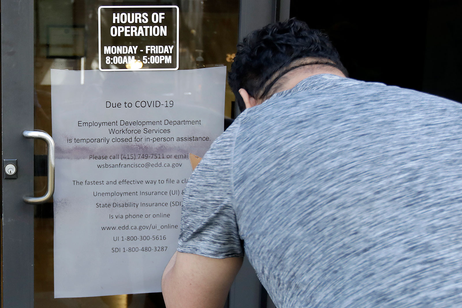 A man takes a photo of a sign outside an Employment Development Department office in San Francisco on March 26.