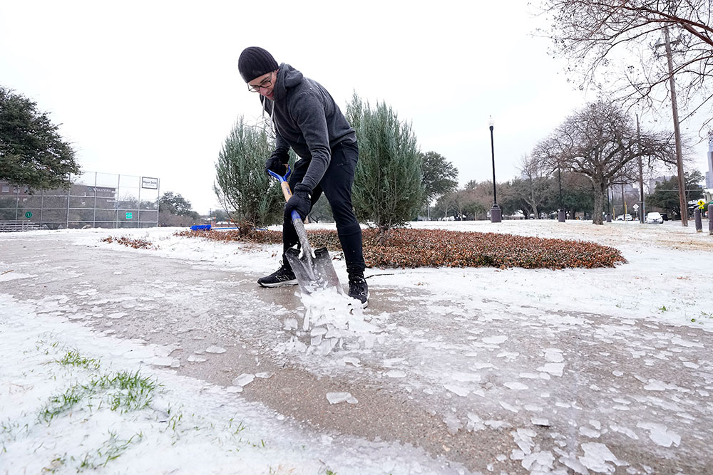 Joshua Lang shovels ice off a public walkway leading into a neighborhood park near his home in Dallas, Texas.