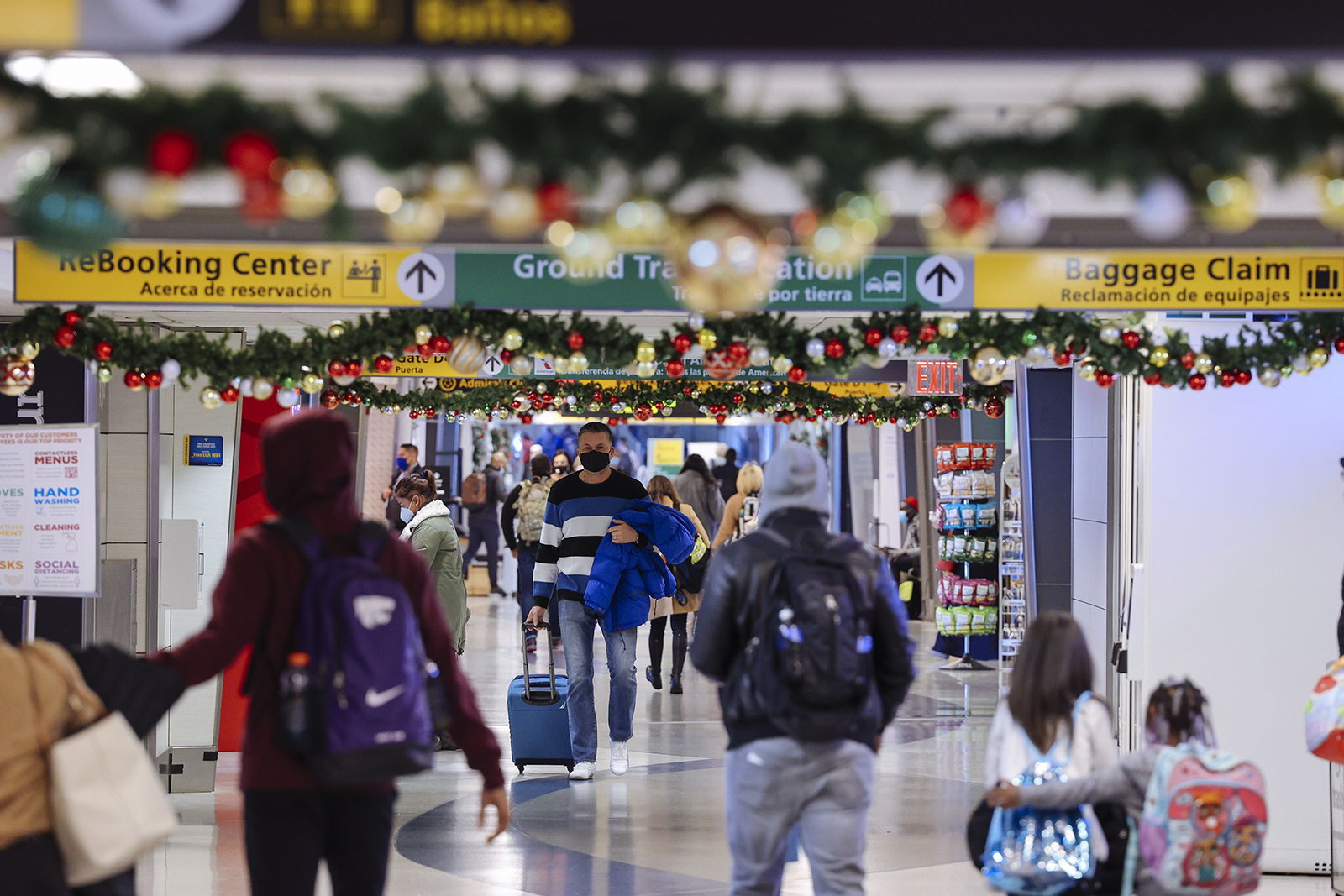 Travelers wearing protective masks walk through LaGuardia Airport (LGA) in New York, on  December 24.