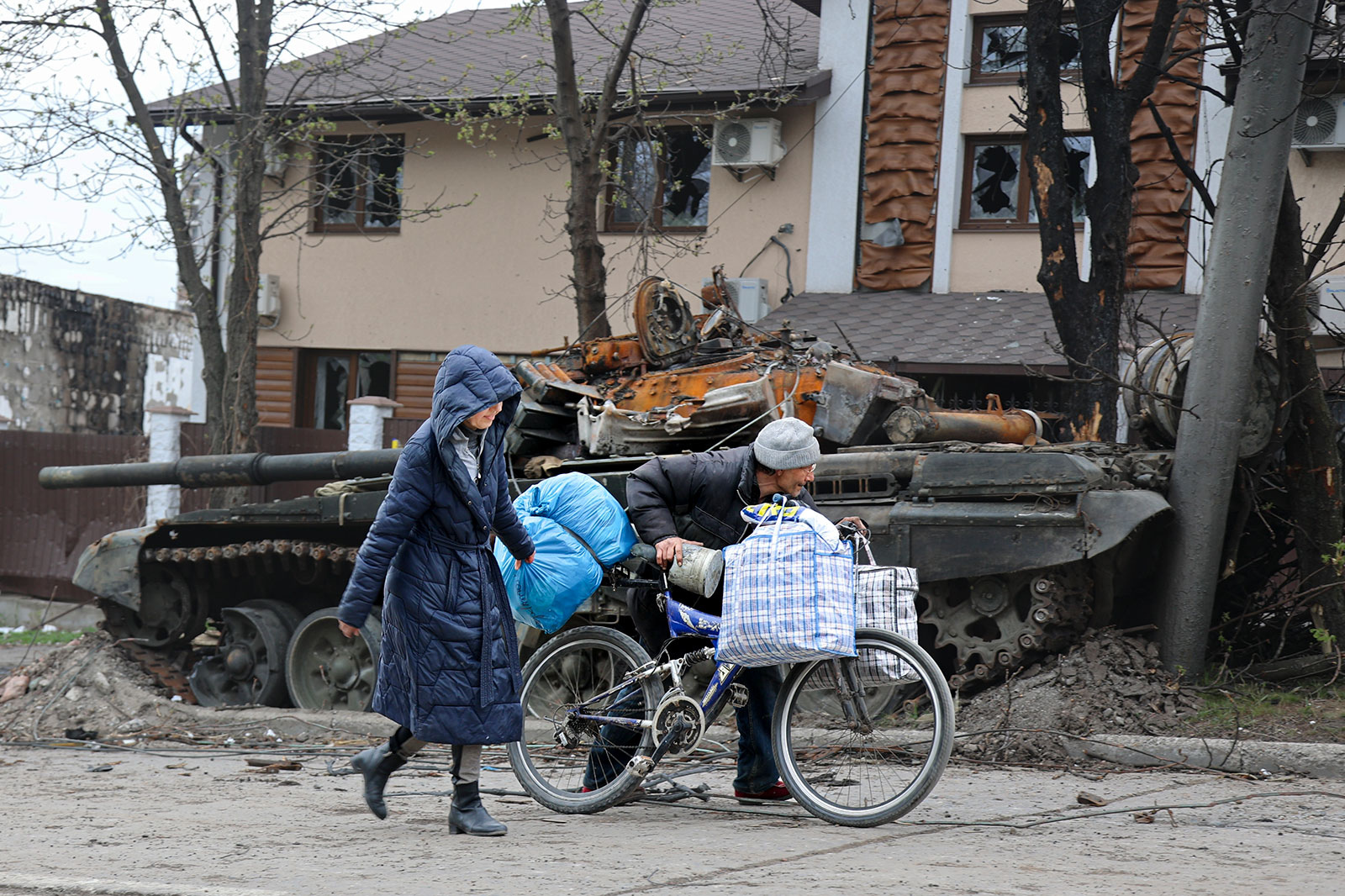 Local civilians walk past a tank destroyed during heavy fighting in Mariupol, Ukraine, on Tuesday, April 19. 