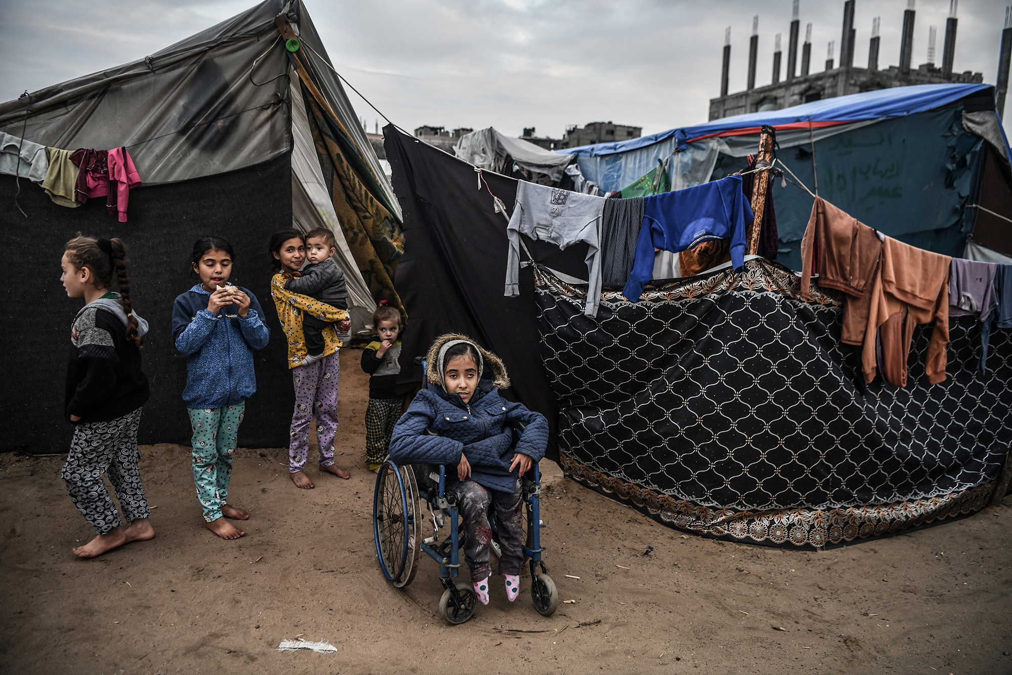 16-year-old Palestinian Nida Abid, center, who was born with a walking disability, is seen with a wheelchair amid the makeshift tents in Rafah, Gaza on February 5. Abid and her family left their homes and took refuge in Rafah.