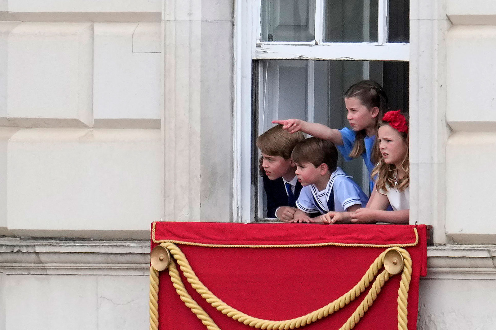 Britain's Prince George of Cambridge, left, Britain's Princess Charlotte of Cambridge, second from right, and Britain's Prince Louis of Cambridge, second from left, watch from a window of Buckingham Palace as the troops march past during the Trooping the Colour.