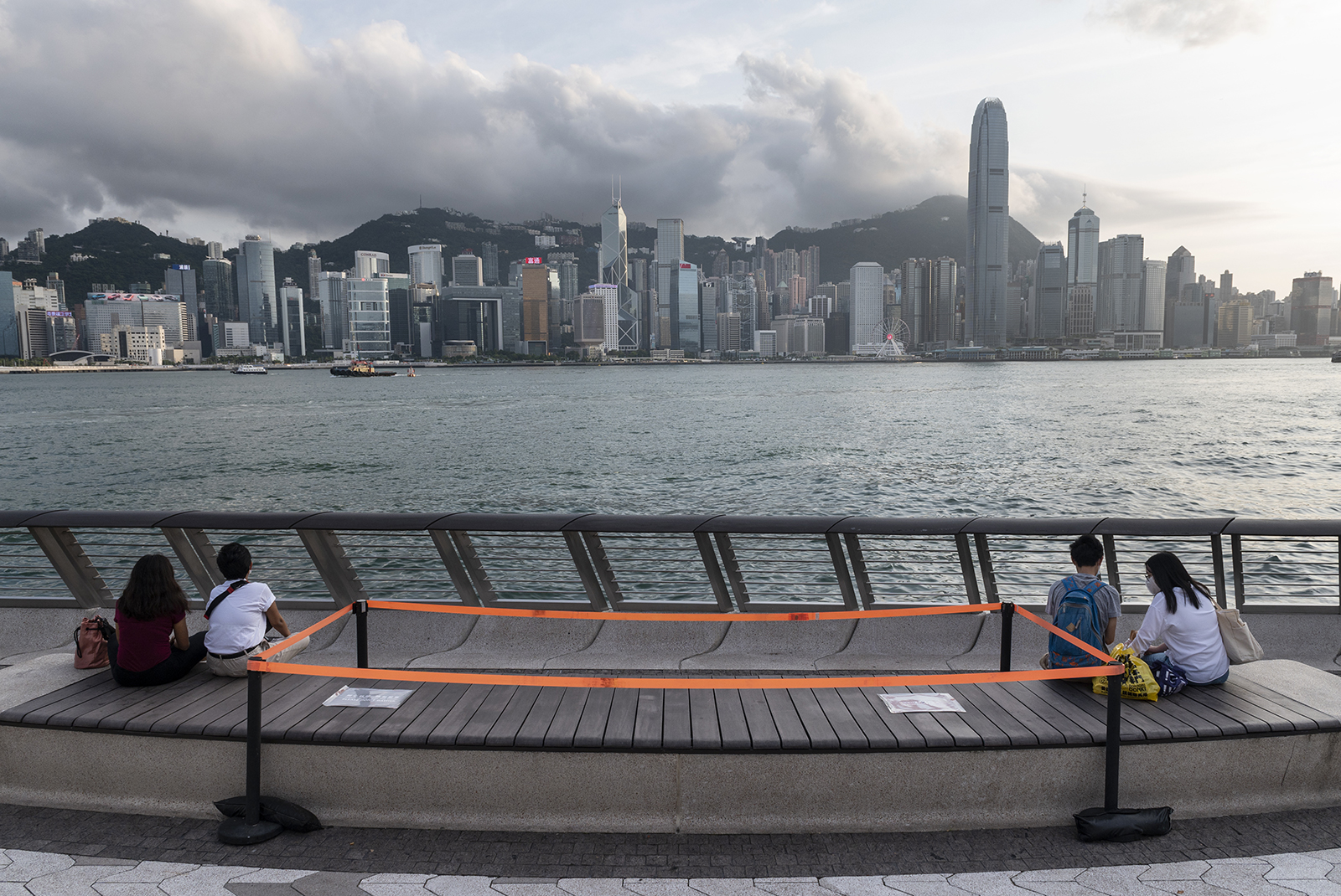 Couples sit and enjoy the view of he Victoria harbor as public benches are seen with orange tape to block access to them in Tsim Sha Tsui, Hong Kong, China, on August 24.