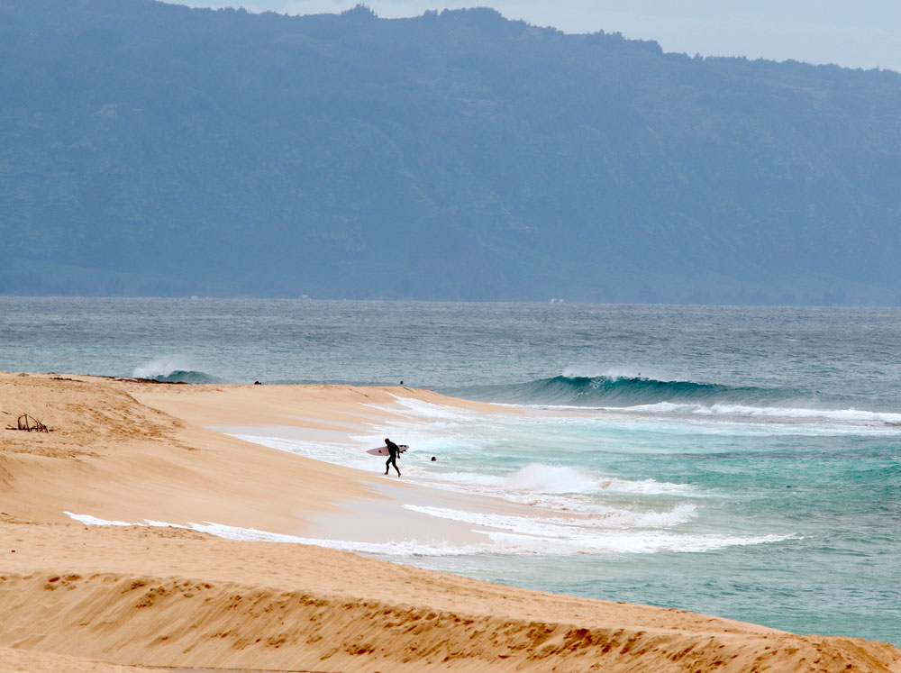 A surfer walks out of the ocean on Oahu's North Shore near Haleiwa, Hawaii, on Tuesday, March 31. 