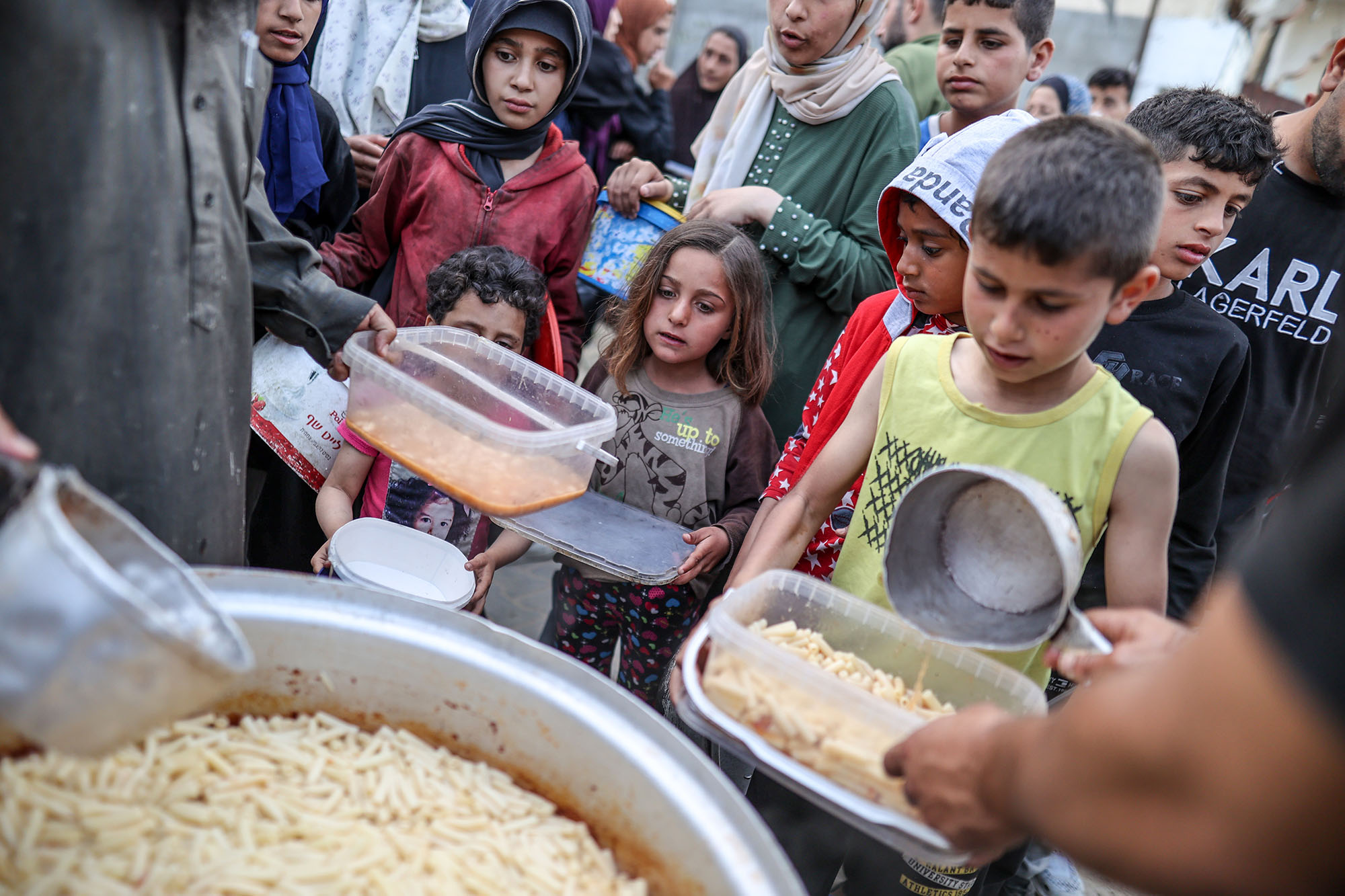 Palestinian children wait to receive food distributed by charity organizations in Deir Al Balah, Gaza, on April 1.