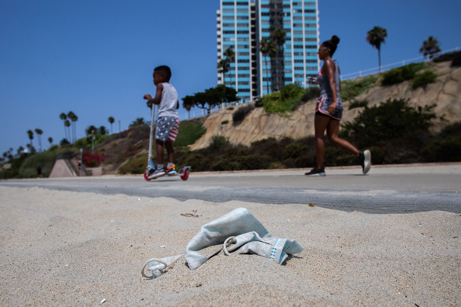 A woman and her son walk by a discarded face mask in Long Beach, California on August 22.