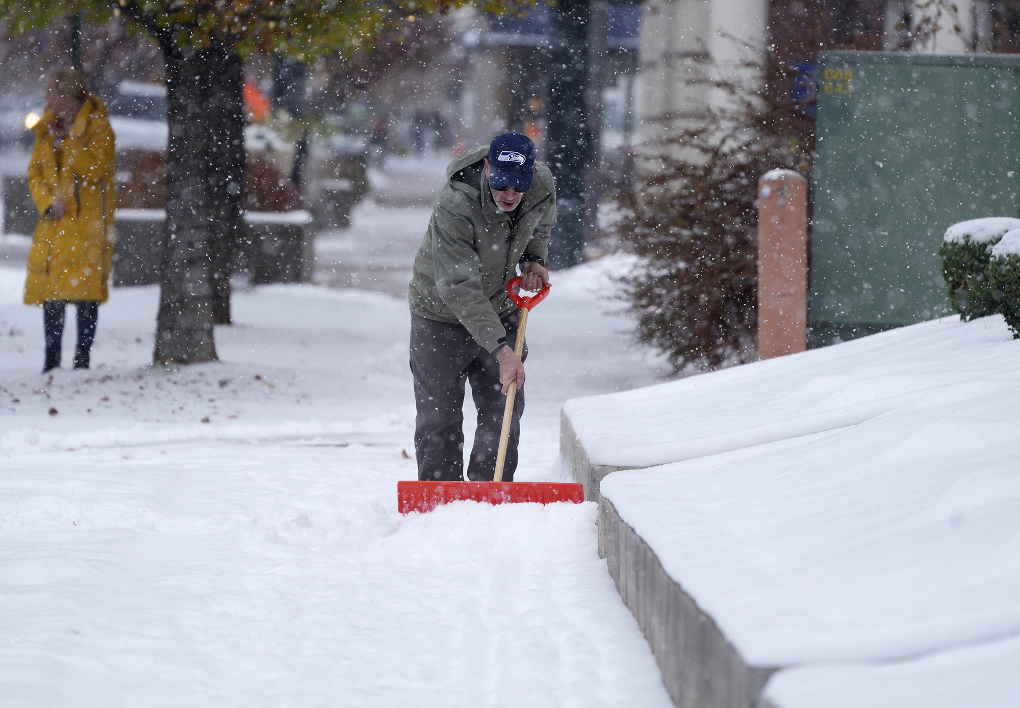 A homeowner clears snow from a walkway in Denver on Thursday. 