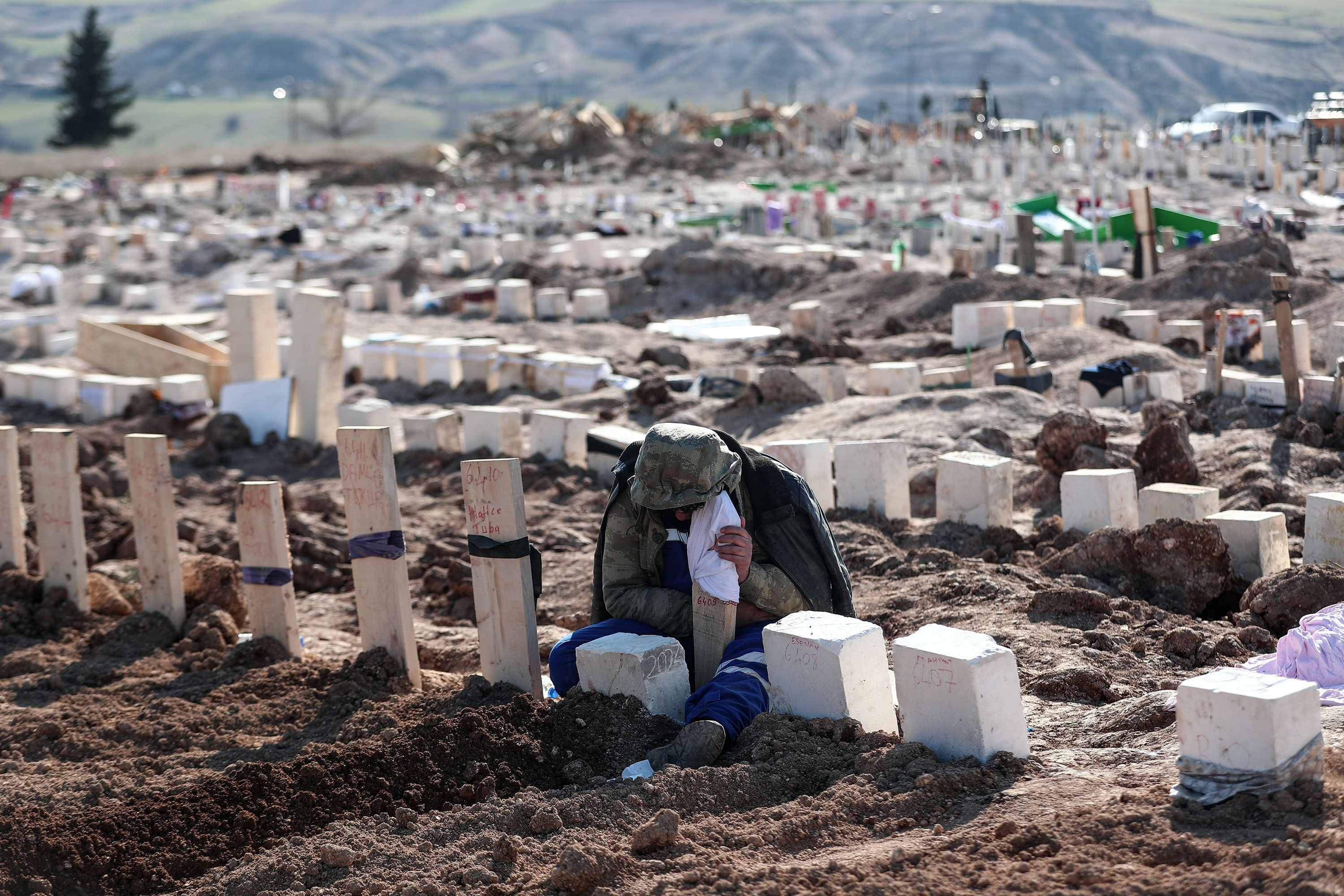 People mourn their relatives at a mass grave in Adiyaman, Turkey, on February 11. 