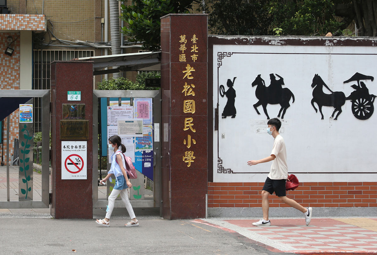 Students wearing face masks walk past a closed primary school in Taipei, Taiwan on May 18.