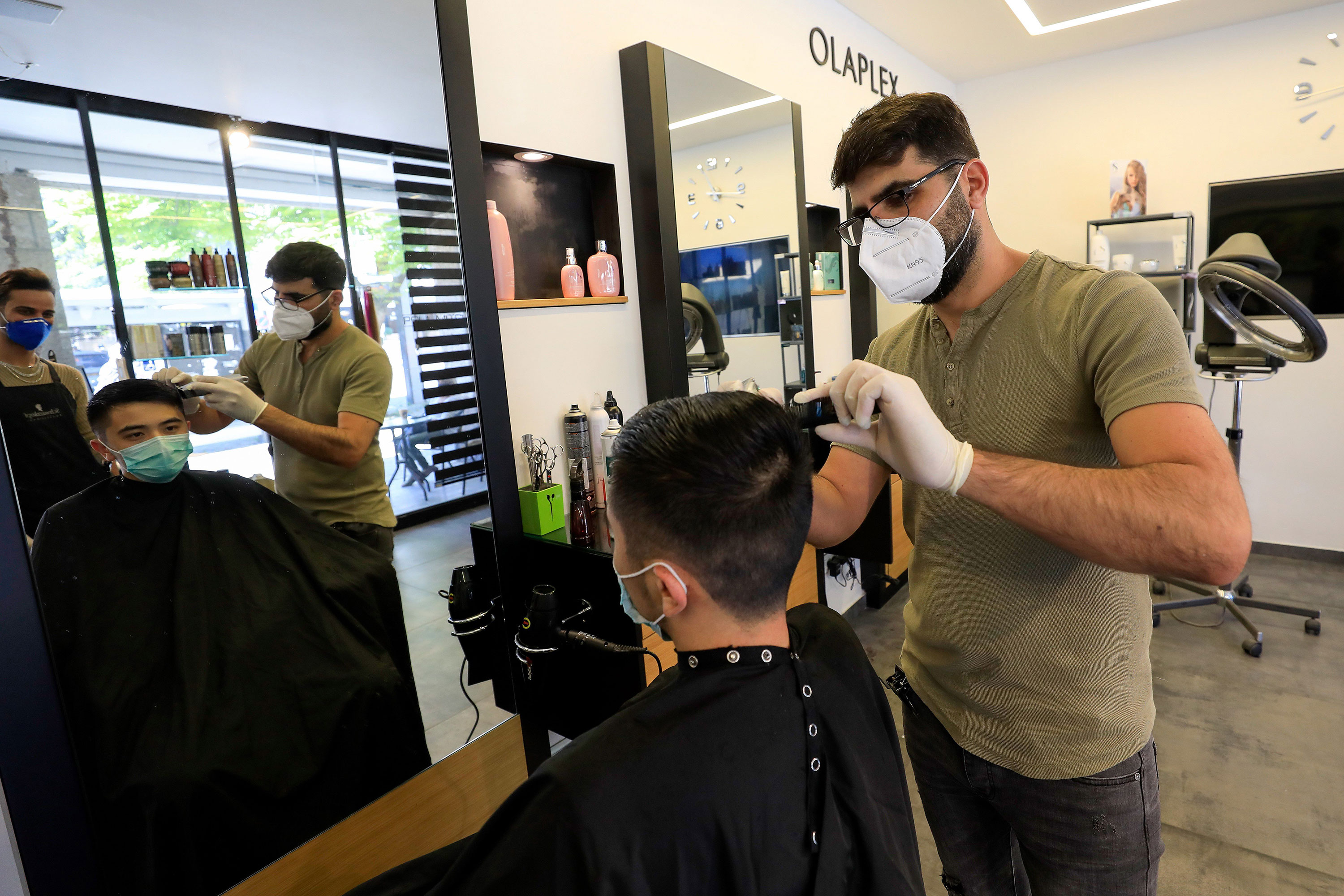 A hairdresser cuts a customer's hair in his shop in Jerusalem on April 26.