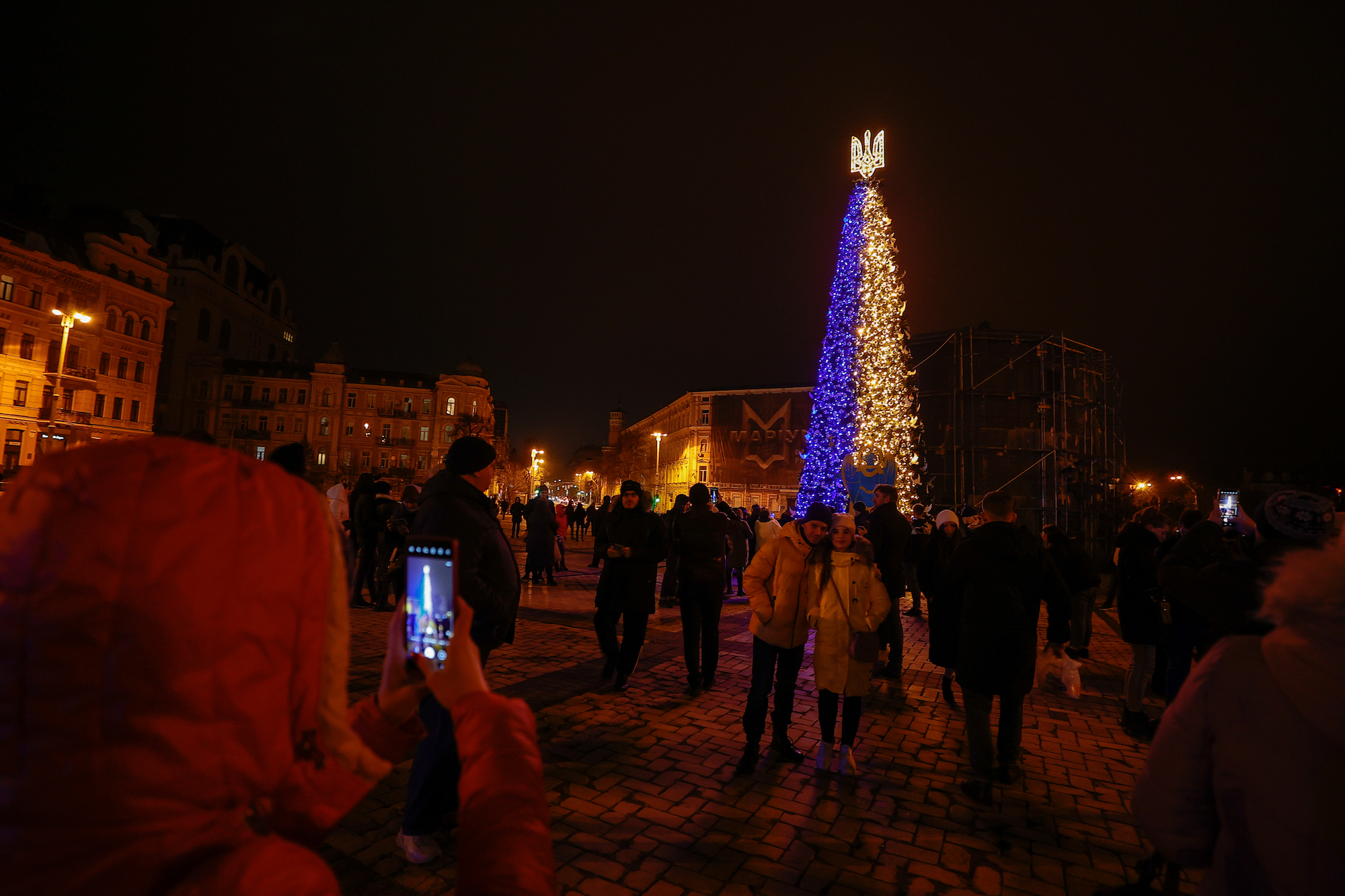 People take photos in front of the recently-illuminated Christmas tree at Sophia Square in Kyiv on Sunday.
