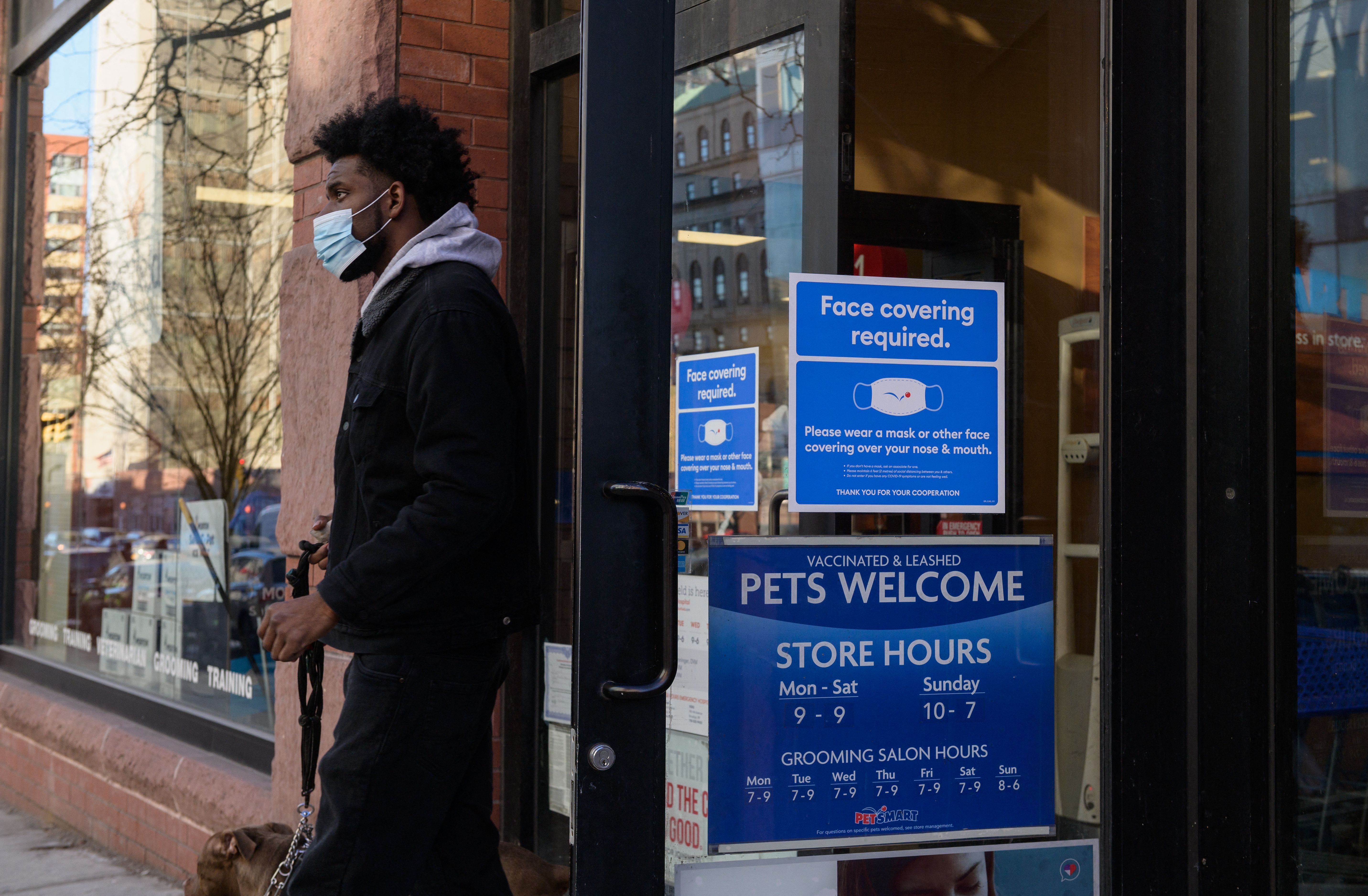 A store in New York City posts its mask requirements, in January. person wearing a face mask leaves a store on January 26, 2022 in New York City. 