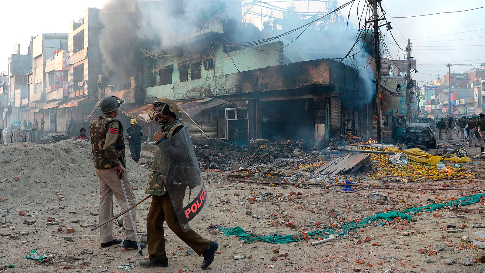 Policeman stand in front of vandalized shops following clashes between supporters and opponents of a new citizenship law in the Bhajanpura area of New Delhi on February 24.