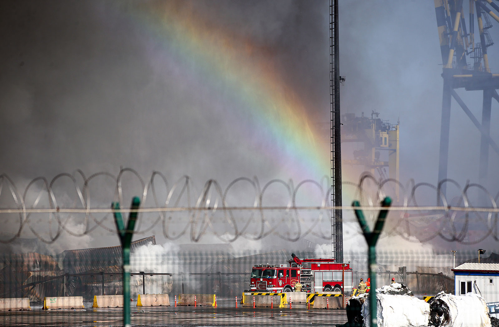 A rainbow appears as firetrucks work to extinguish a major fire that broke out at the Iskenderun port.